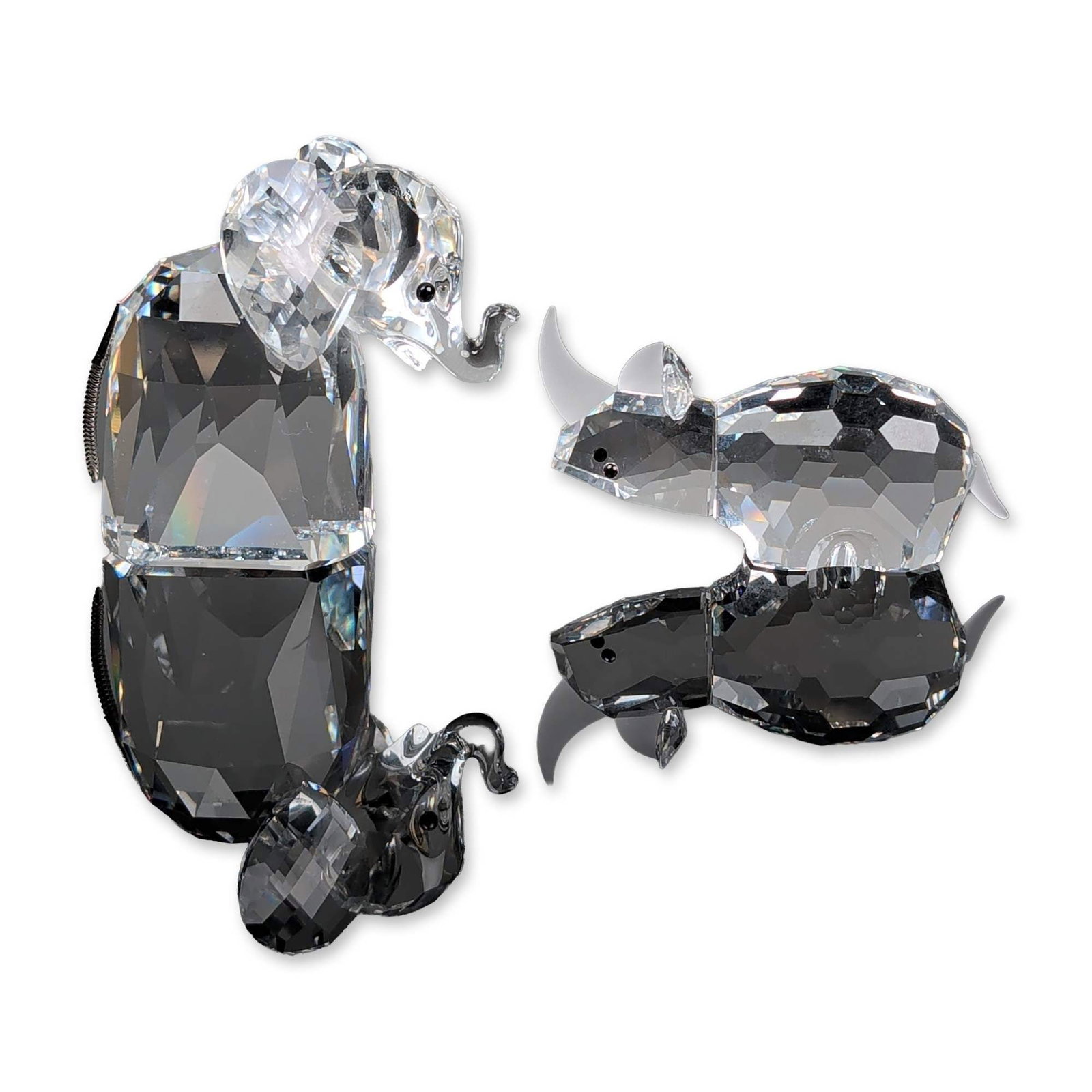 2pc Swarovski Silver Crystal Animal Figurines: Swarovski Silver Crystal. Two animal figurines from the African Wildlife series, including an elephant and a rhinoceros. The elephant is rendered in multi-faceted clear crystal with a raised trunk, bl