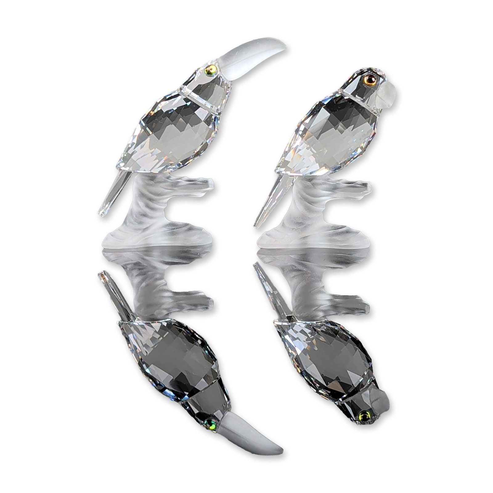 2pc Swarovski Silver Crystal Figurines, Toucan and Parrot: Two faceted lead crystal bird figurines from the Silver Crystal series, featuring a toucan and a parrot. Each bird is depicted perching on a frosted crystal branch base with multi-faceted clear lead c