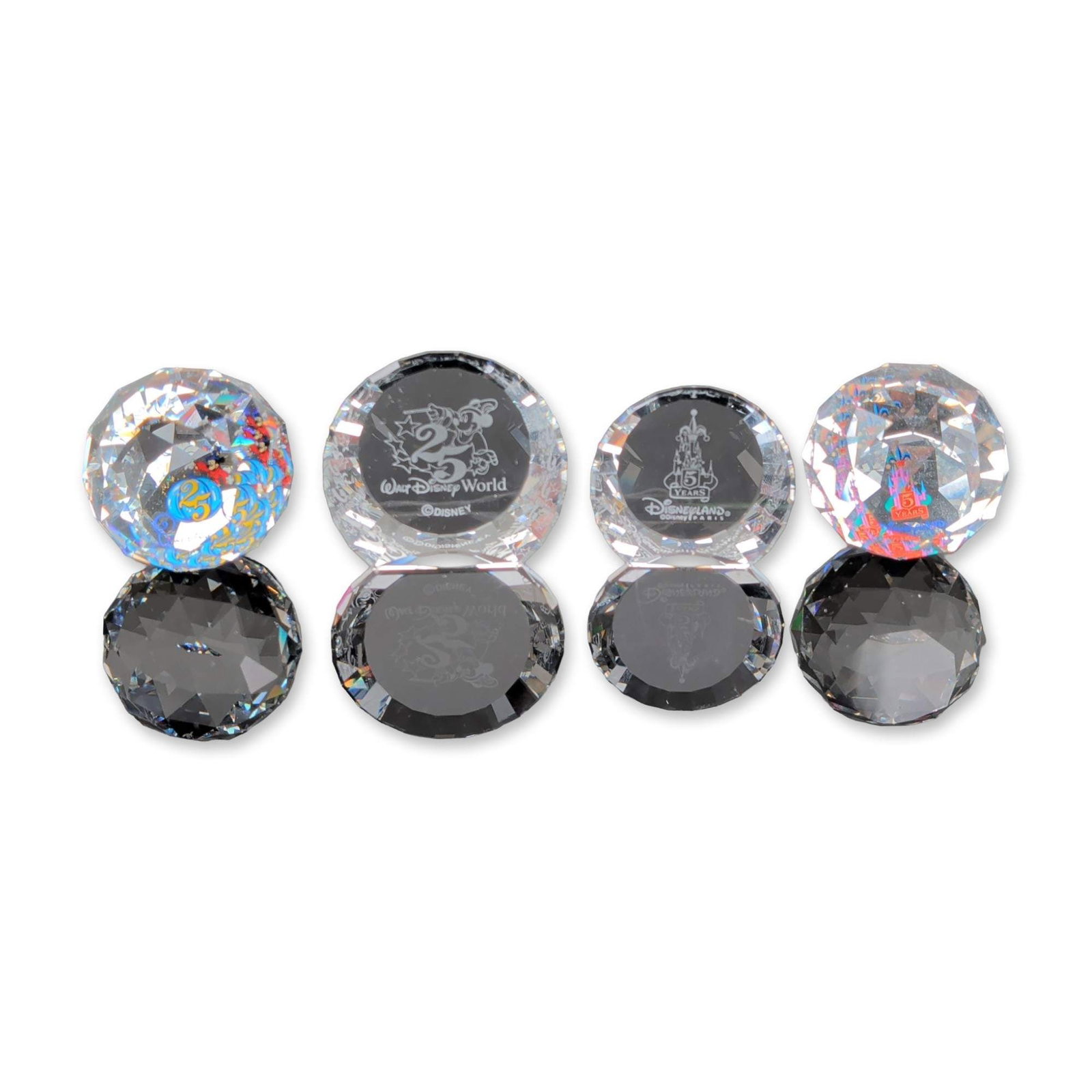 4pc D. Swarovski & Co. Disney Crystal Paperweights: Four faceted lead crystal paperweights commemorating the Walt Disney World 25th Anniversary and the Disneyland Paris 5th Anniversary. The collection includes two briolette-cut spherical weights with c