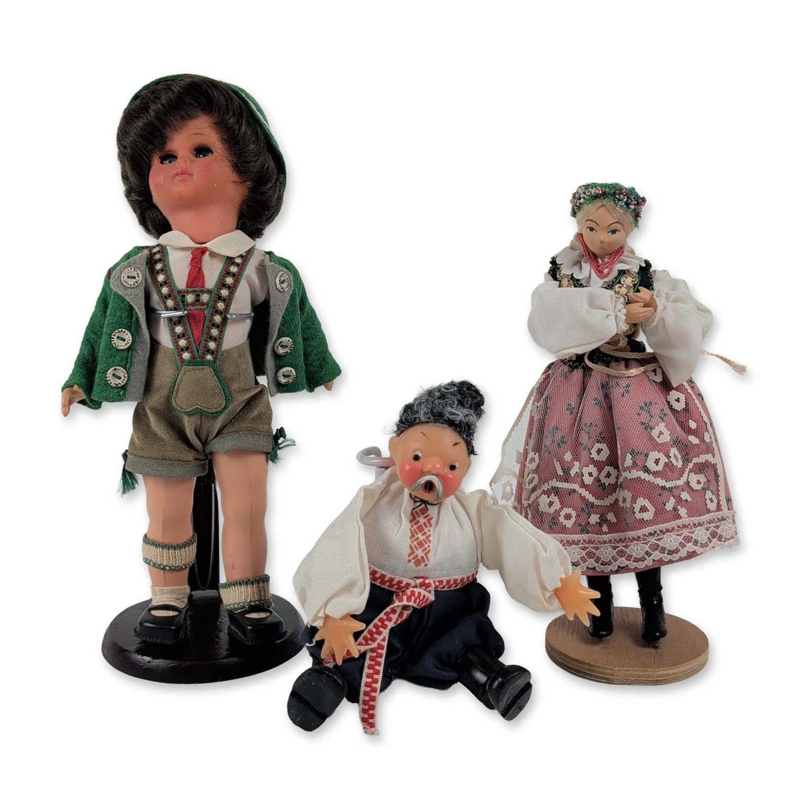 Trio of International Folk Costume Souvenir Dolls: This set of three souvenir dolls showcases European folk traditions from Germany, Poland, and Russia. The first is a Bavarian boy doll made of vinyl with a jointed body, sleepy eyes, and a synthetic w