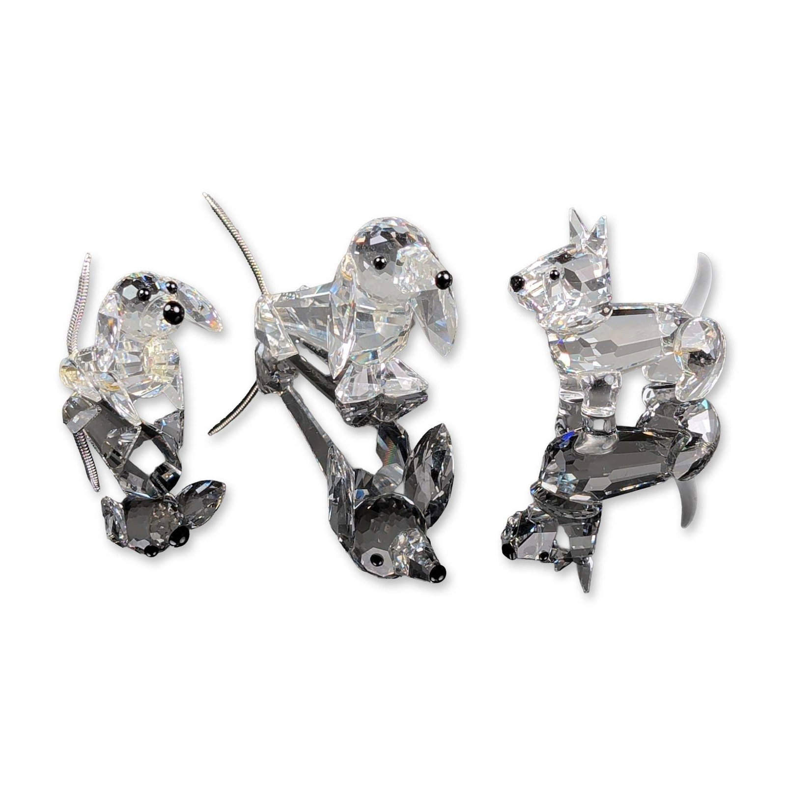 3pc Swarovski Crystal Dog Figurines: Three Swarovski faceted clear lead crystal dog figurines including a dachshund, a puppy, and a Scottish terrier. The dachshund and puppy feature silver-tone coiled metal wire tails and black bead acce