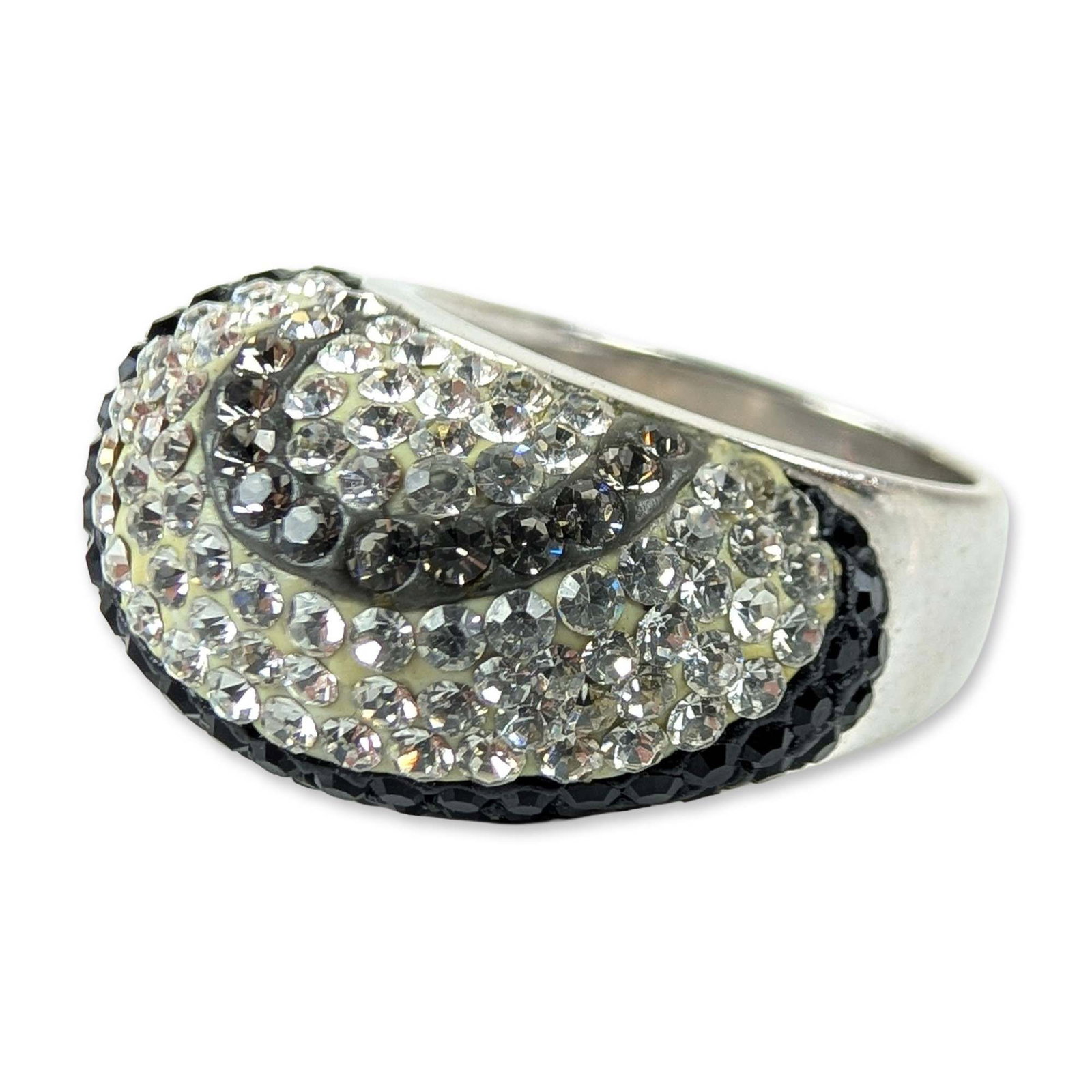 JCM Sterling Silver Pave Swirl Cocktail Ring: JCM (Thailand). Cocktail ring in sterling silver featuring a bold domed head with a stylized wave pattern. The design is set with contrasting bands of clear and black round faceted stones in a pave