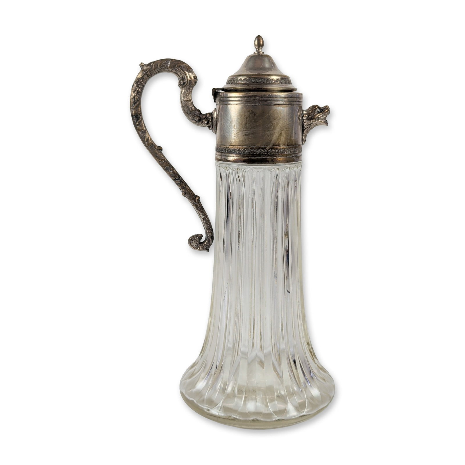 Edwardian Silver Mounted Fluted Glass Claret Jug: An Edwardian-style claret jug crafted from fluted glass with silver-toned metal mounts, showcasing a tall body with vertical molded fluting that widens toward a broad base. The metal mount features a 