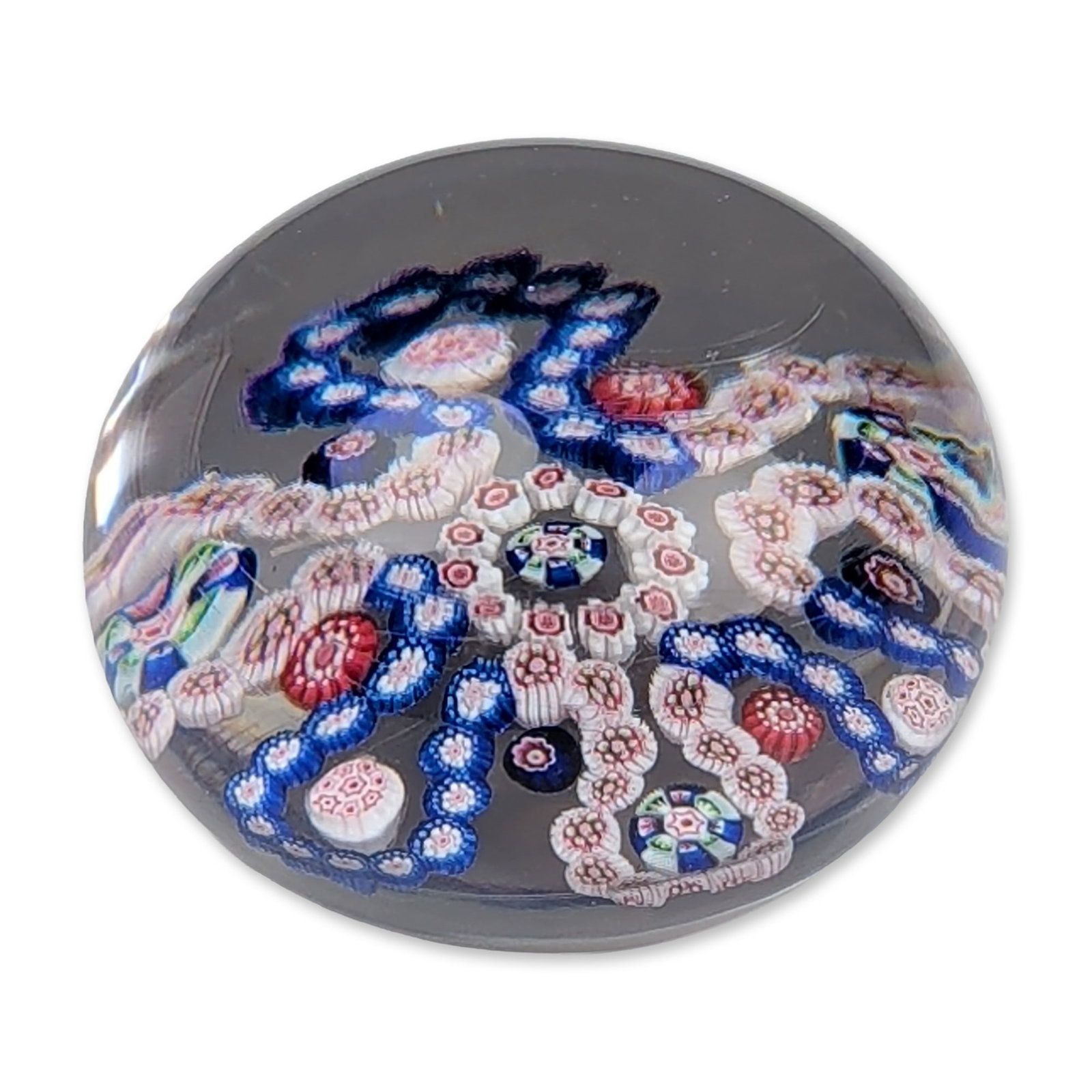 Baccarat Antique Garland Millefiori Paperweight: Baccarat, France, mid-19th century. Antique garland millefiori paperweight in clear glass, featuring a central motif surrounded by six interlocking garland loops. The complex arrangement consists of w
