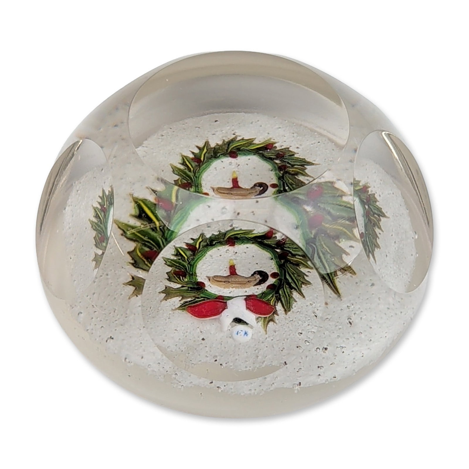 Lewis Kain Faceted Glass Christmas Wreath Paperweight: Lewis Kain (American, 20th century). Art glass paperweight, circa 1980, featuring a faceted clear glass dome set over an opaque white ground. The internal lampwork decoration depicts a festive Christm