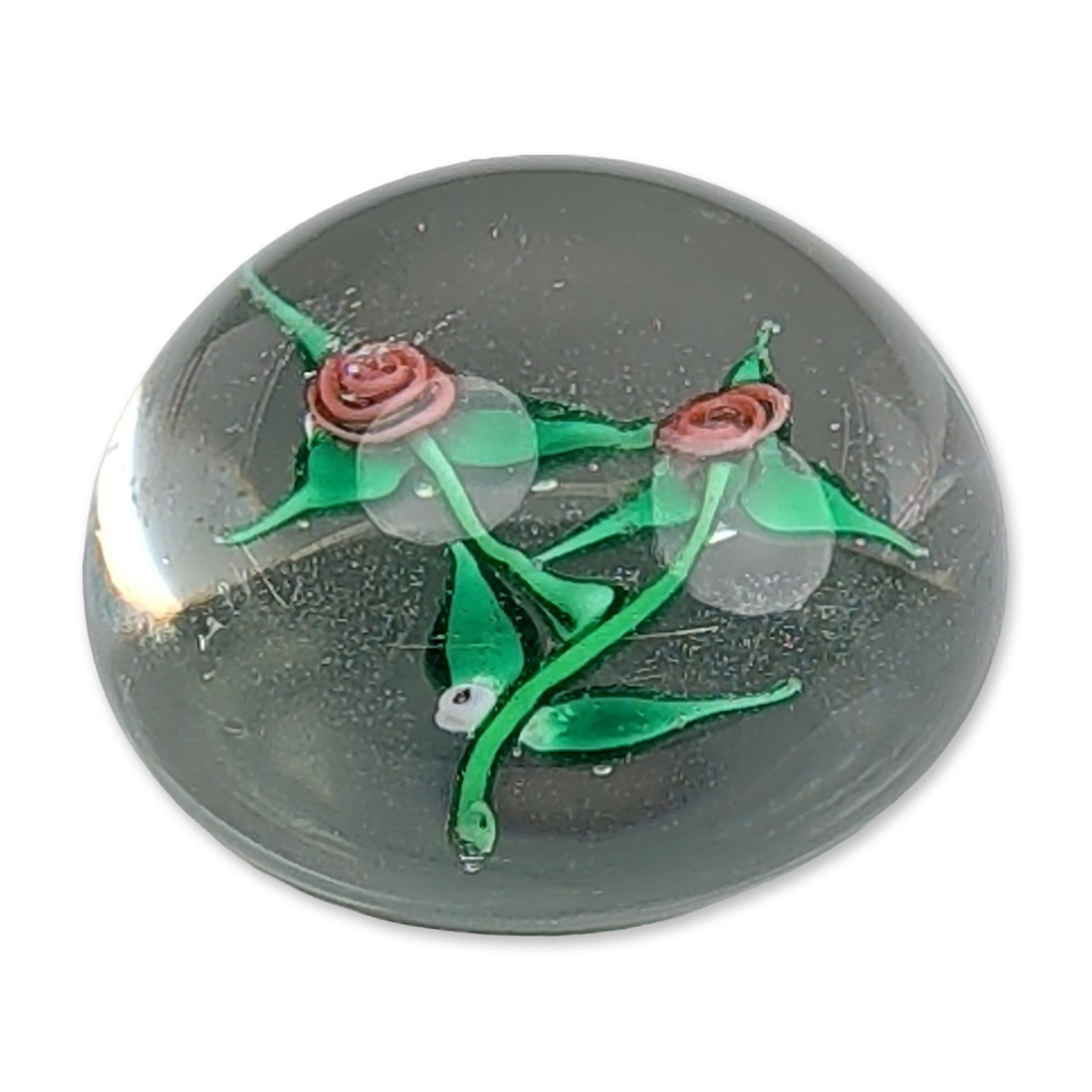 Ray Banford Miniature Lampwork Rose Paperweight: Miniature paperweight in clear art glass, featuring internal lampwork decoration of two red roses with green stems and leaves. A worn paper label on the base is inscribed in handwritten ink, reading #