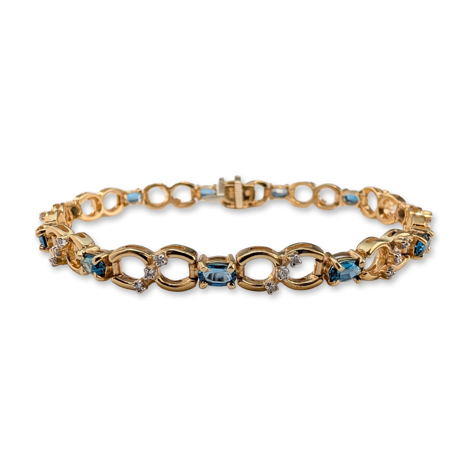 14K Gold Blue Topaz and Diamond Bracelet: Link bracelet in 14 karat yellow gold, featuring eleven oval-cut blue topaz stones in four-prong settings. The gemstones alternate with pairs of small round brilliant-cut diamond accents set within op
