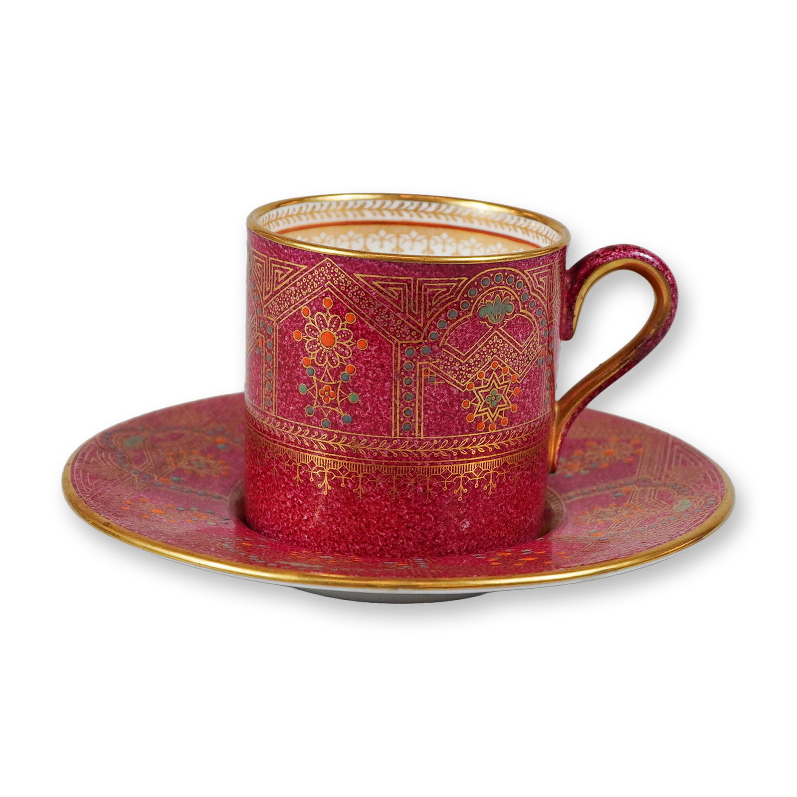 Wedgwood Bone China Cup and Saucer Set, Persian Pattern: A Wedgwood bone china cup and saucer set decorated in an Orientalist or Persian style pattern. Both pieces feature a magenta ground stippled with a gold diaper pattern. The decoration consists of geom