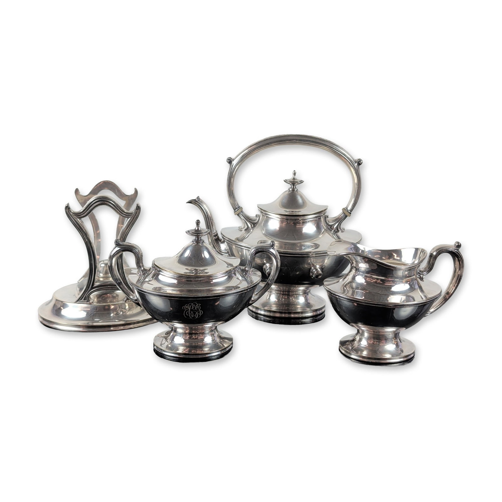 3pc Reed & Barton Silverplated Tea Service with Stand Pattern #3882: The set has a melon-ribbed body with ornate scrolling handles, acanthus leaf details, and pedestal feet. It includes a tilting tea kettle on a stand with a removable spirit burner, a lidded sugar bowl
