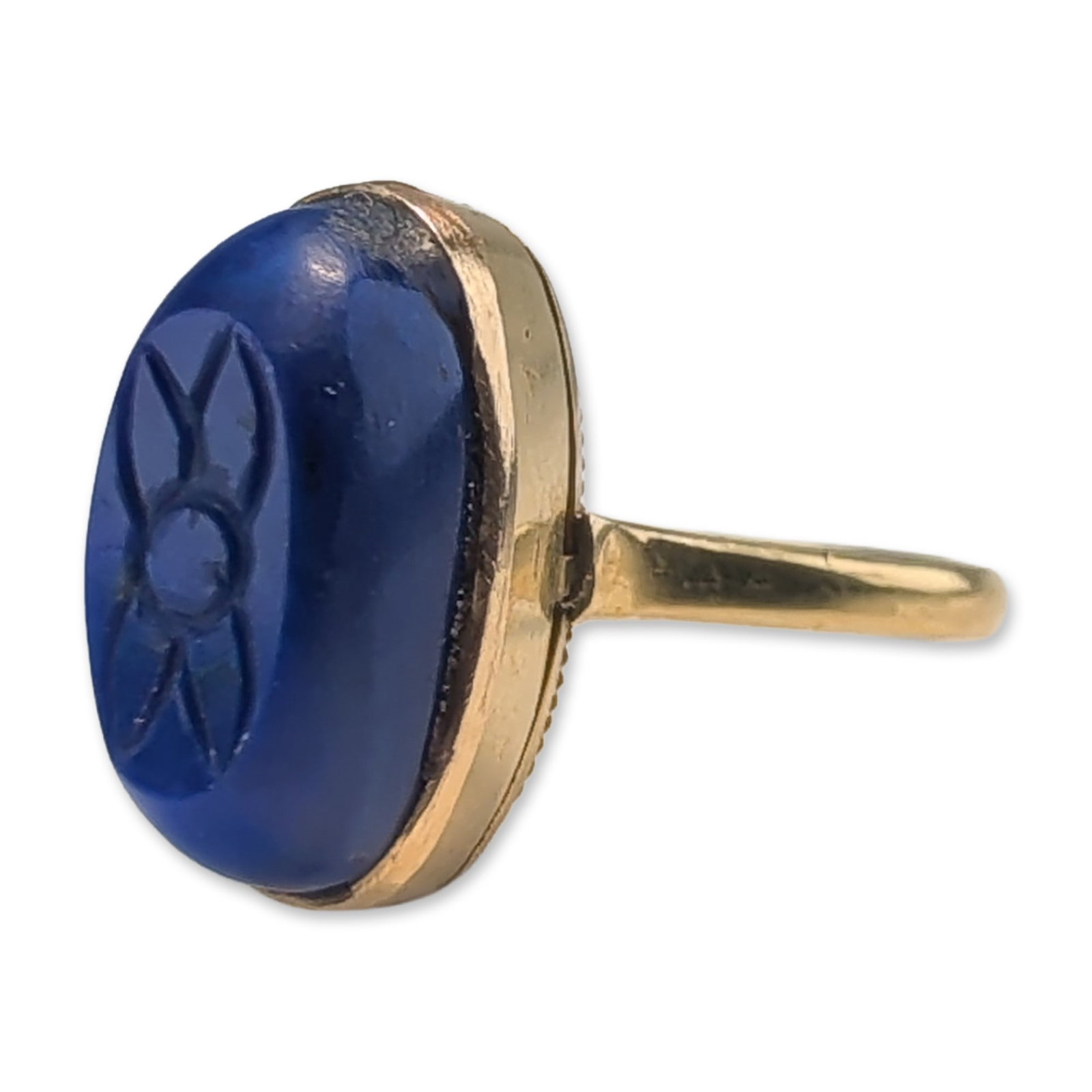 18K Yellow Gold and Carved Lapis Lazuli Ring: 18k yellow gold cocktail ring featuring a large, oval lapis lazuli stone. The stone is decorated with a carved intaglio motif. The stone is bezel-set atop a decorative gallery with vertical fluted pie