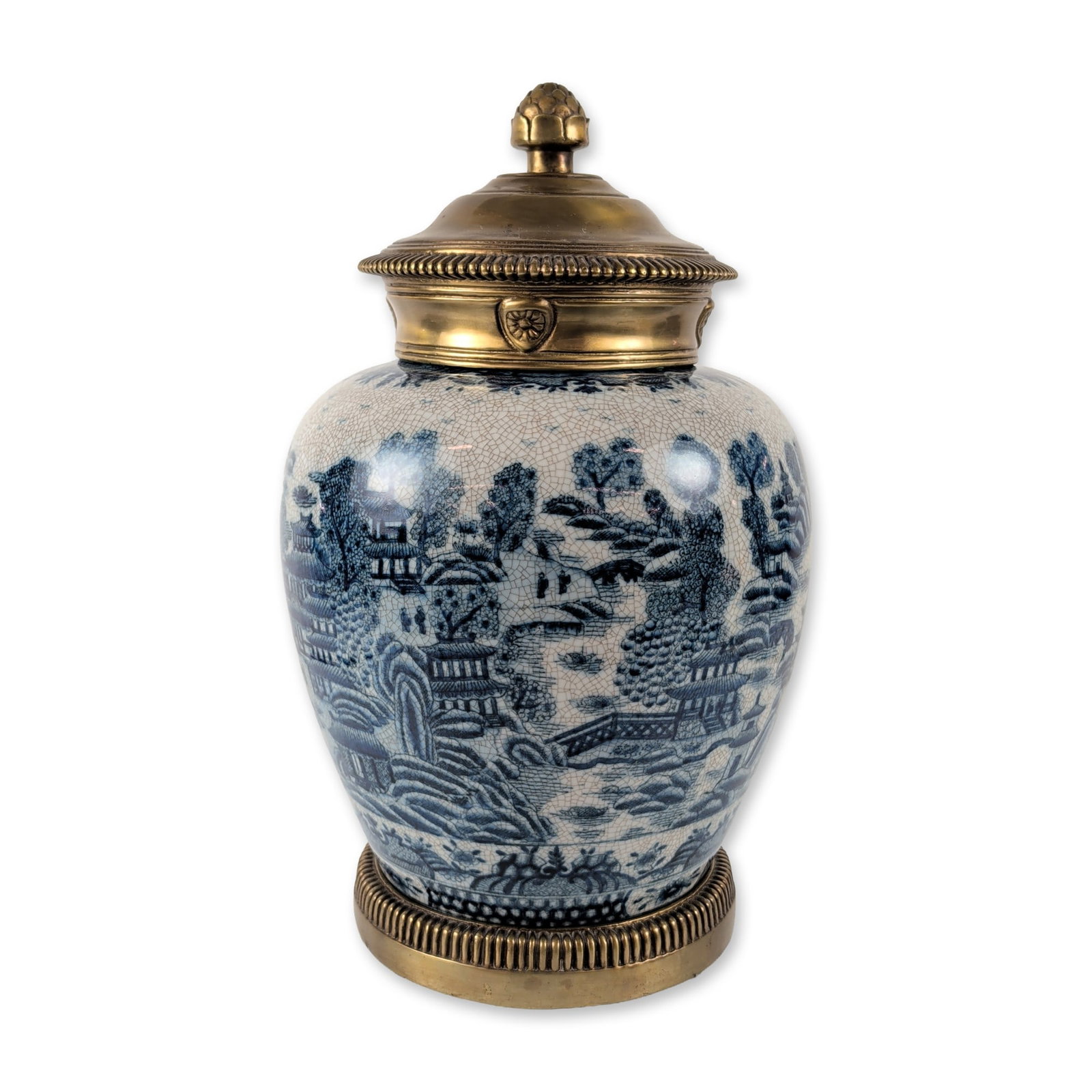 United Wilson Blue Willow Porcelain Jar: Large ovoid decorative jar in blue and white crackle-glazed porcelain, featuring a transfer-printed landscape scene with pagodas and pavilions in the Blue Willow style. The piece is fitted with gilt m