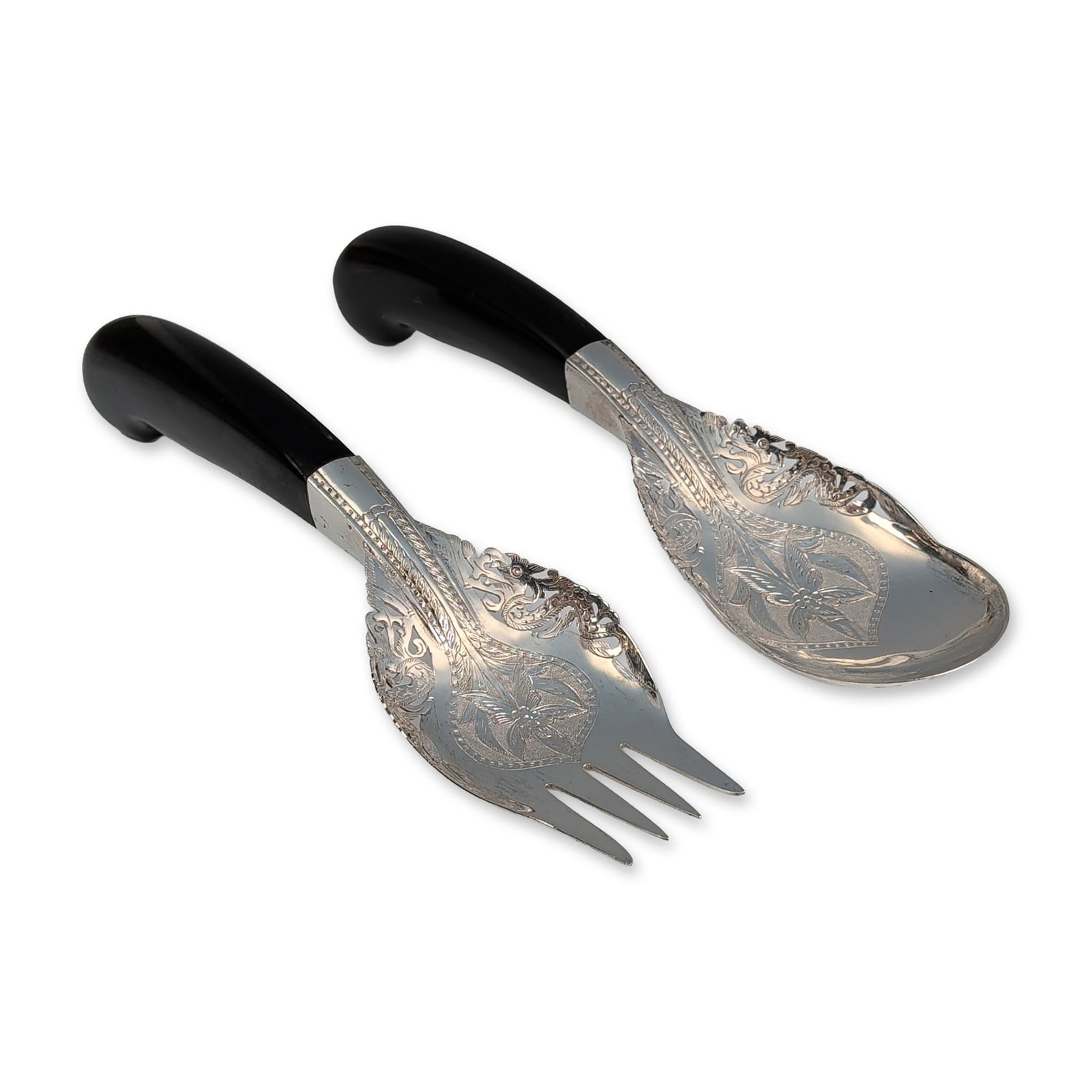 Pair of Mohd Salleh & Sons Malaysian Silver Serving Utensils: Pair of Malaysian silver and horn serving utensils by Mohd Salleh & Sons. The set includes a serving fork and a serving spoon, both featuring silver heads with elaborate hand-chased and repousse flora