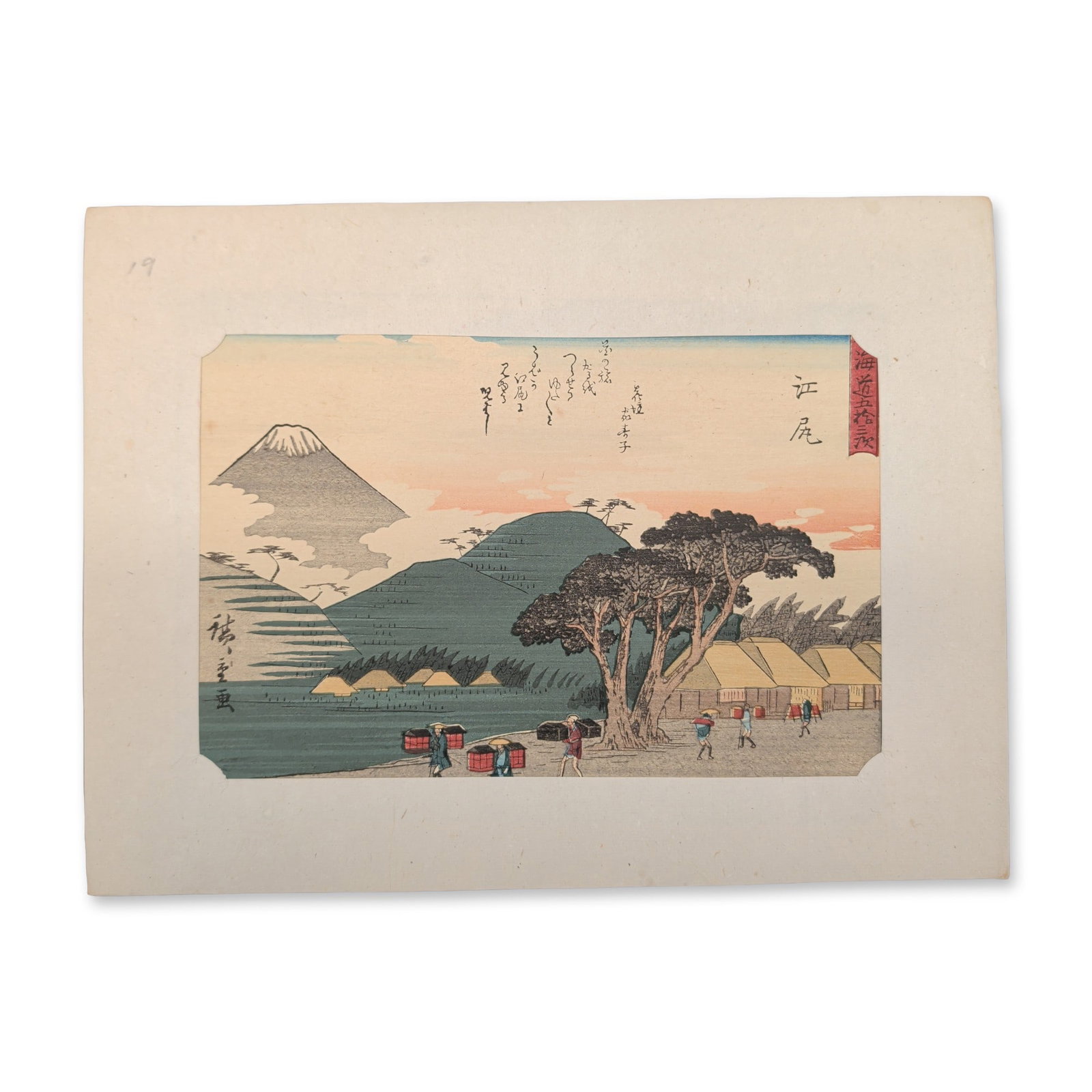 After Utagawa Hiroshige (Japanese 1797-1858) Ejiri from a Fifty-three Stations of the Tokaido Series: A bustling town landscape unfolds with traveling merchants, pack horses, and porters navigating a central street bordered by dense rows of traditional buildings and a sweeping grove of pine trees bene