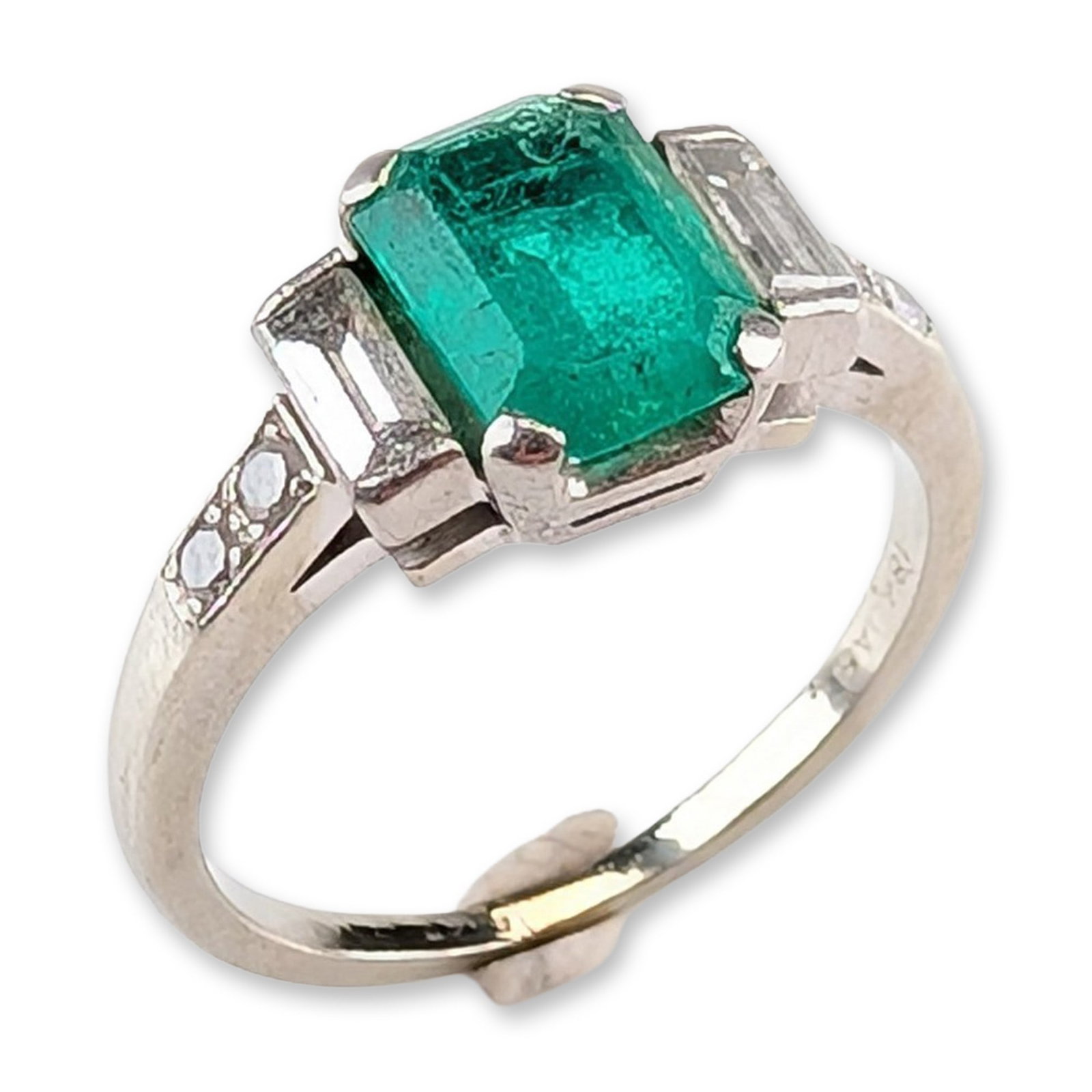 Jabel 18K White Gold Emerald and Diamond Ring: Jabel 18 karat white gold seven-stone ring featuring a central emerald-cut emerald. The emerald is held in a four-prong setting and is flanked by two bar-set baguette-cut diamonds. The shoulders are a