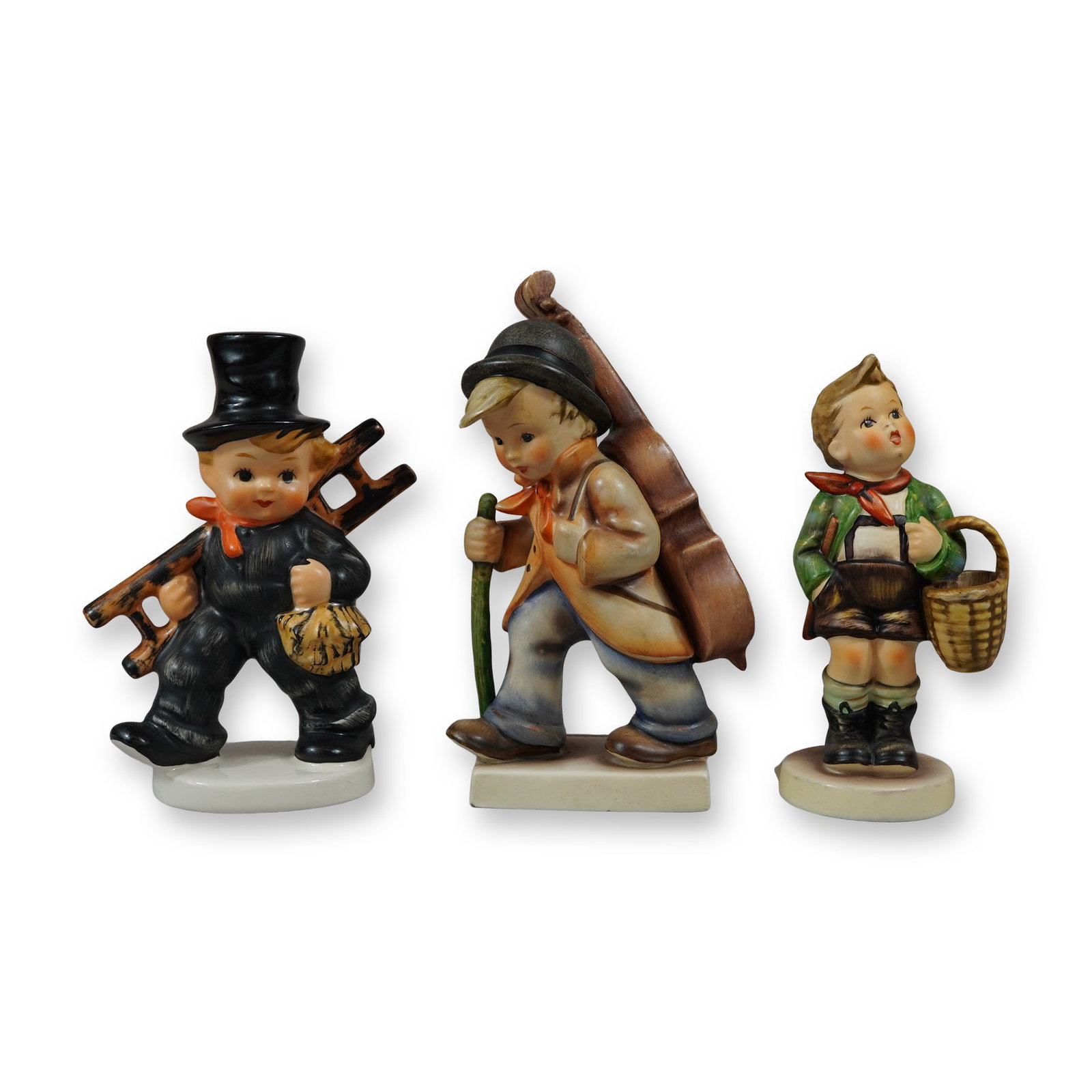 3pc Goebel Hummel Porcelain Figurines: M.J. Hummel for Goebel. Trio of hand-painted porcelain figurines manufactured in West Germany. The collection includes the following models: Chimney Sweep (Hum 12 / 2/0): Depicting a boy in