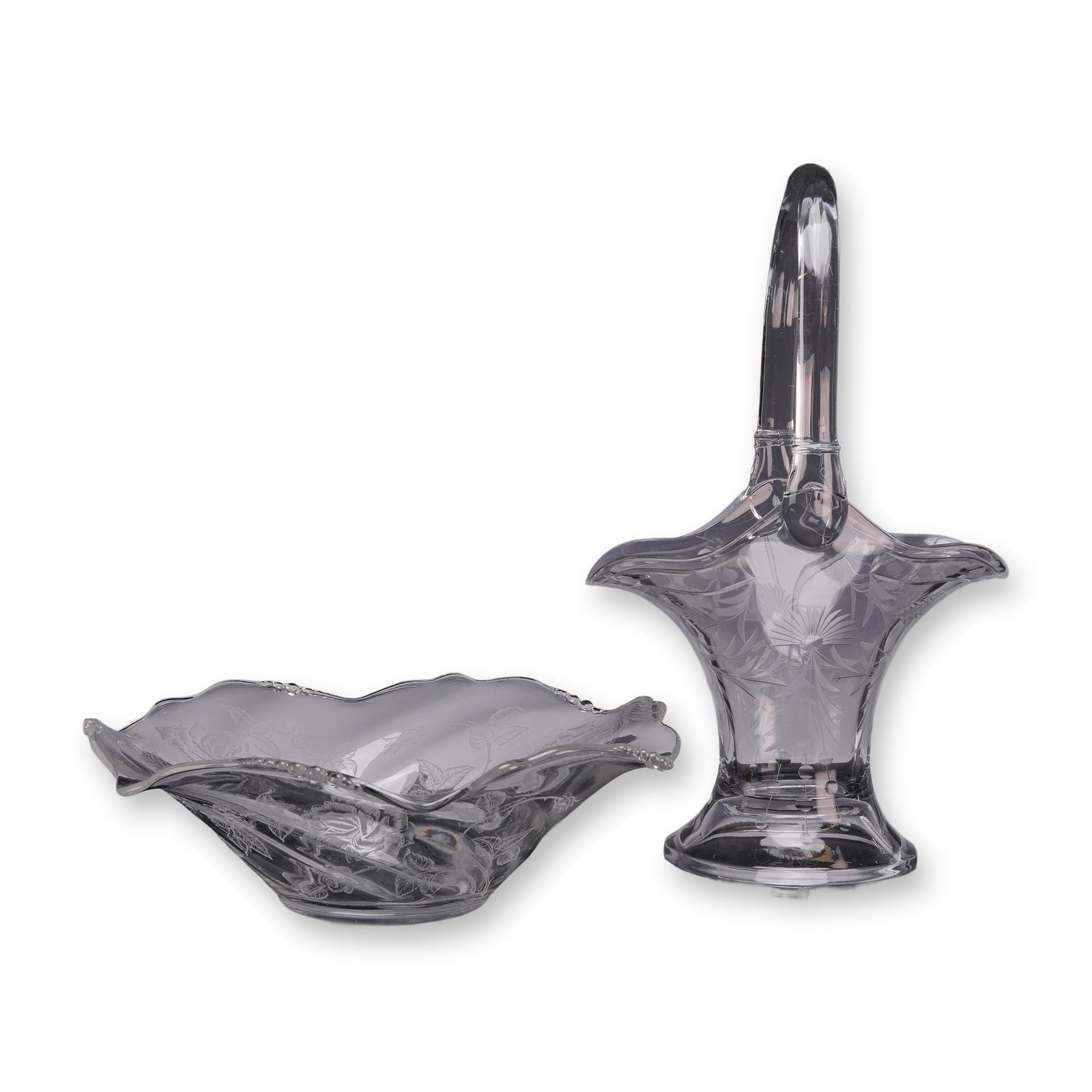Two Floral Accent Heavy Glass Pieces Including a Tall Handled Basket and a Ruffled Bowl: This lot features two pieces of clear etched elegant glass from the mid-20th century. The collection consists of one tall footed basket and one shallow ruffled bowl. The tall basket is constructed of 