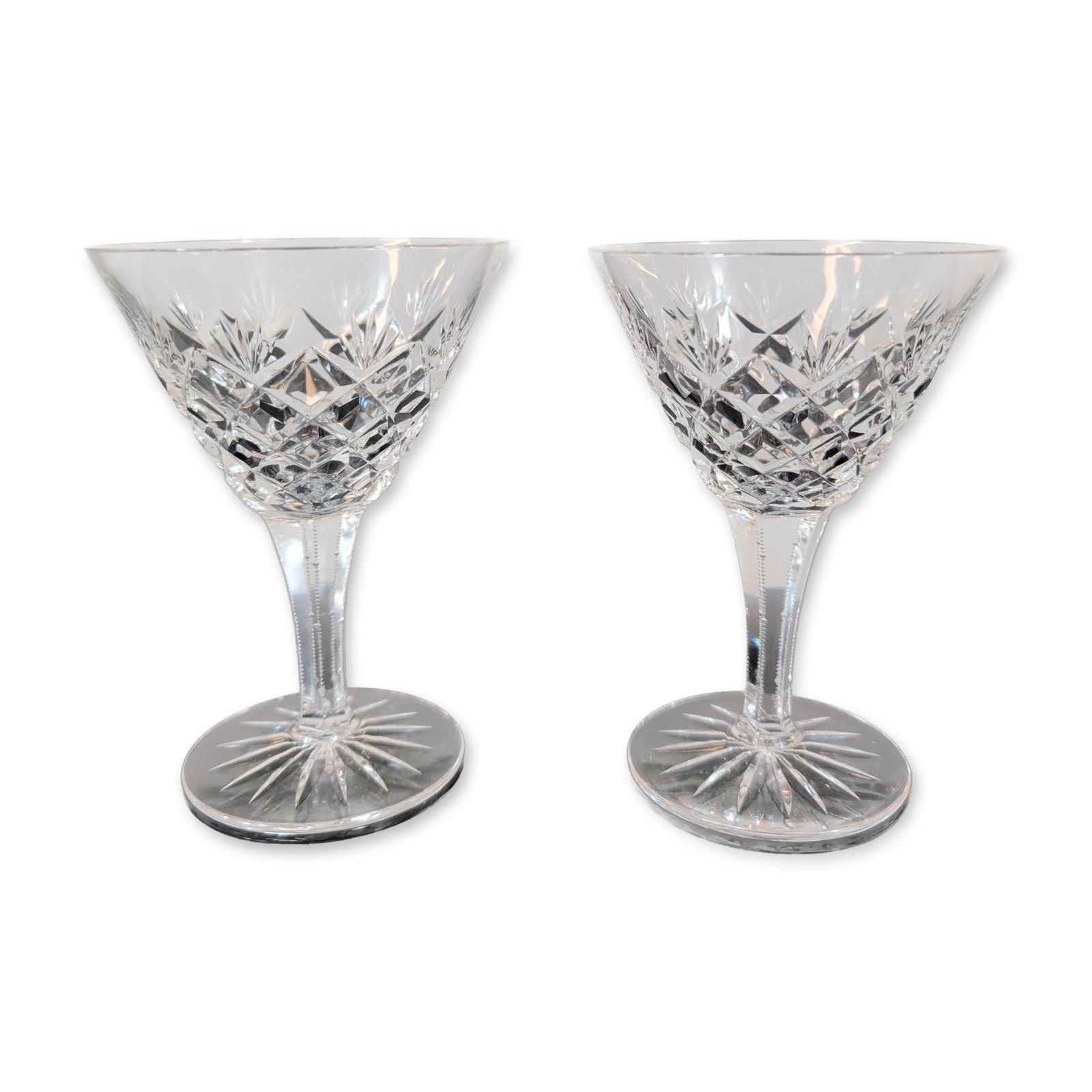 Pair of Cut Crystal Stemmed Coupes: A pair of cut crystal stemmed goblets featuring a classic cut design. Each goblet features a flared bowl decorated with a central band of deep diamond-cut cross-hatching surmounted by a row of