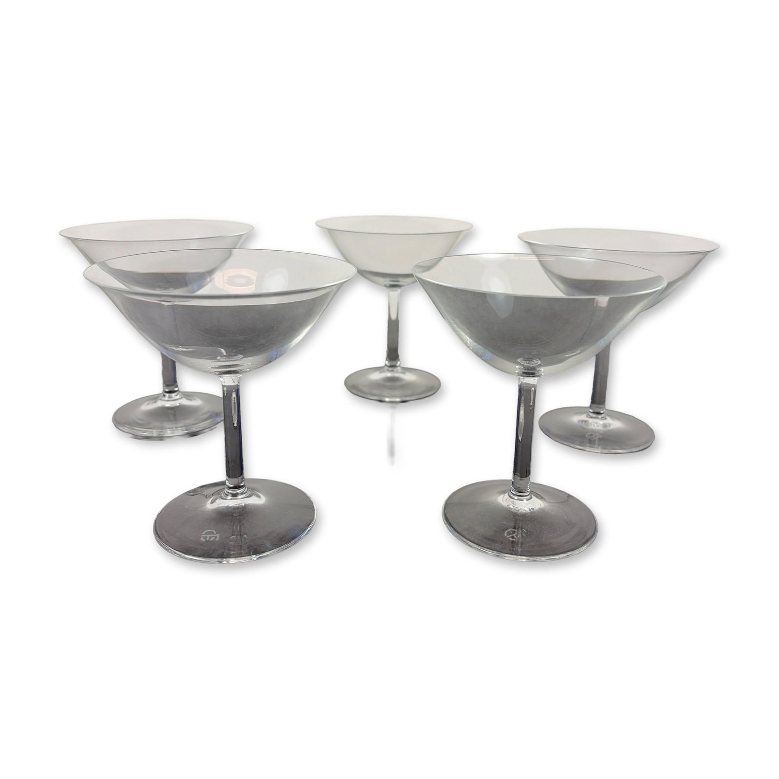 Set of Five Contemporary Glass Cocktail Coupe Glasses: Set of six contemporary clear glass cocktail coupes. Each vessel features a wide, shallow bowl on a slender pulled stem terminating in a flat circular base. Every glass bears a sandblasted CE mark on