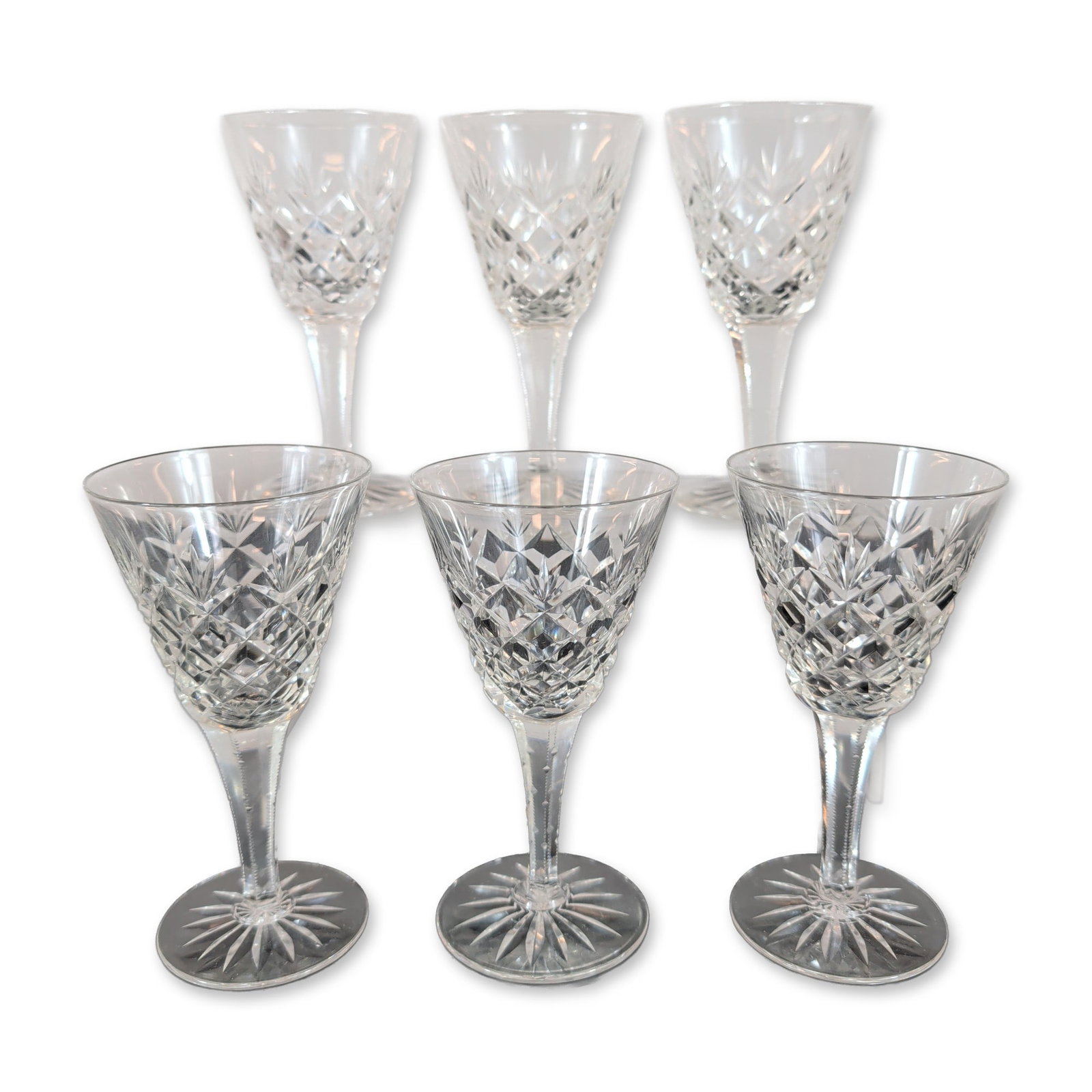 Set of Six Cut Crystal Sherry Glasses: A set of six lead crystal Sherry Glasses. Each glass features a bowl decorated with diamond-cut bands and vertical fan motifs, supported by a multi-faceted stem with notched edges. The circular feet a