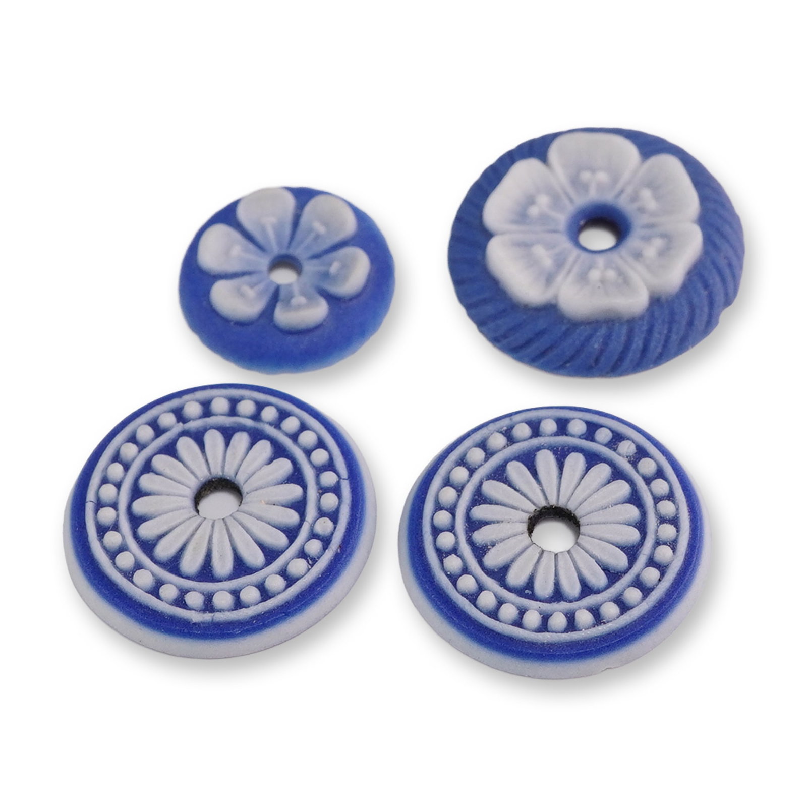 Group of Four Jasperware-Style Medallions: Group of four blue jasperware-style stoneware medallions featuring white sprigged relief decoration. The assortment includes two matching circular medallions with a stylized daisy wheel motif within