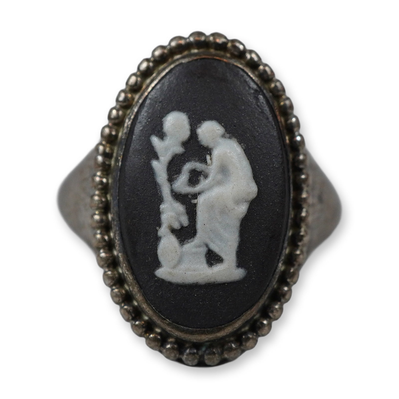 Wedgwood Black Jasperware and 72% Silver Cameo Ring: A Wedgwood black jasperware cameo ring featuring an oval ceramic plaque with white bas-relief decoration. The classical scene depicts a draped female figure. The plaque is secured in a bezel setting