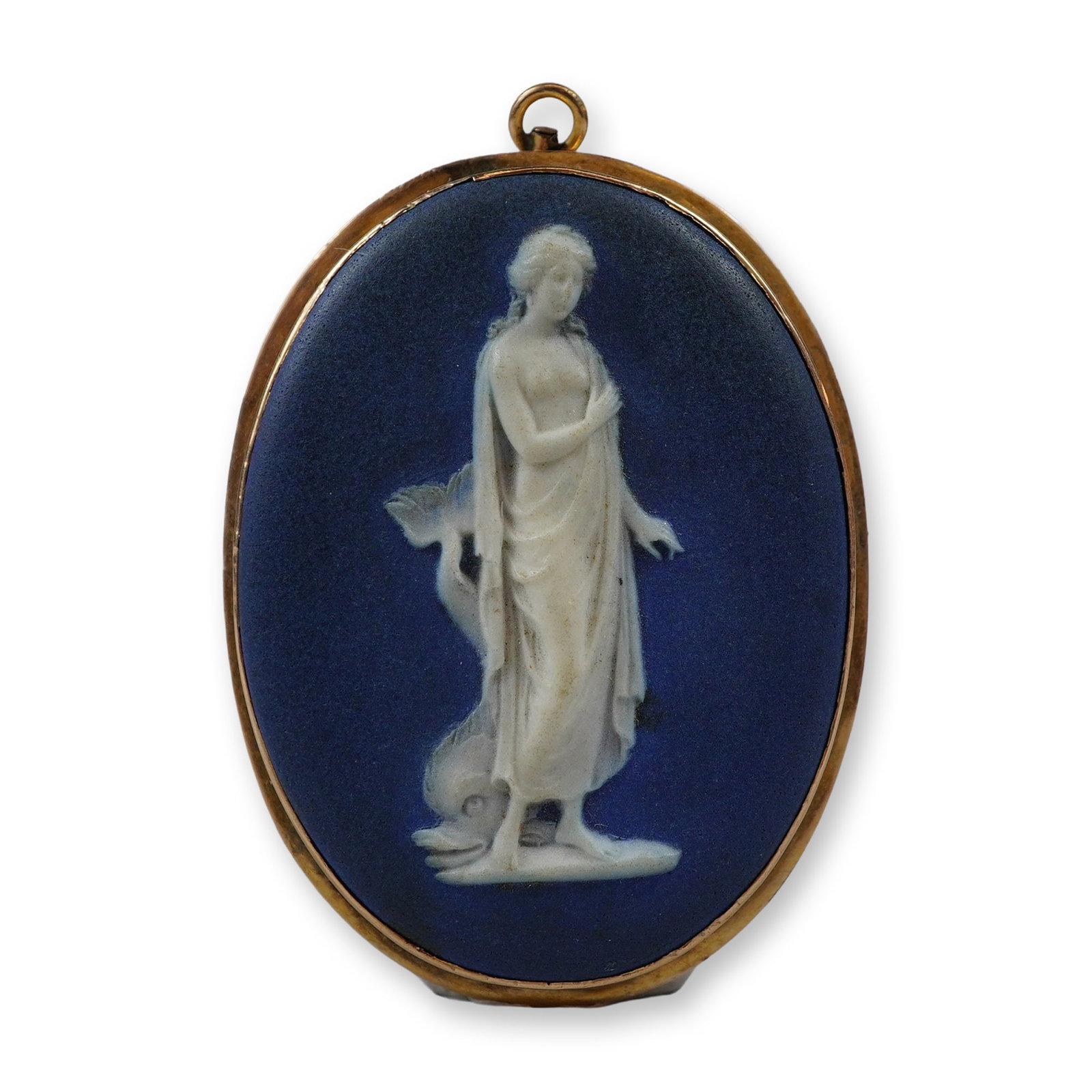 Wedgwood Blue Jasperware Cameo Gold-Plated Pendant-Brooch: A vintage combination pendant and brooch manufactured by Wedgwood. The item features an oval jasperware stoneware plaque in cobalt blue with a white bas-relief depiction of a classical draped female