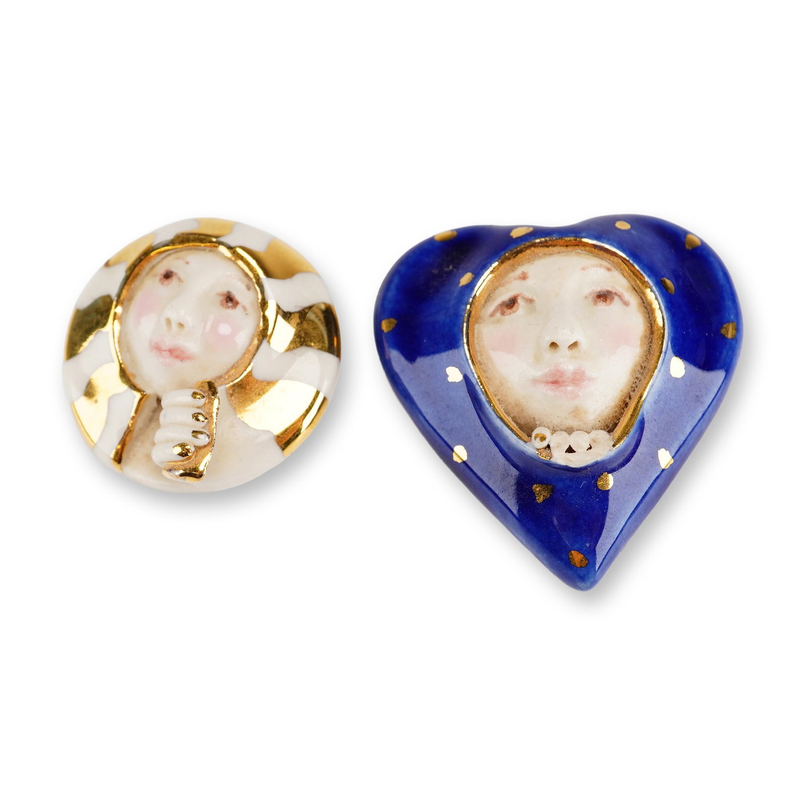2pc Georgia Landau Porcelain Masked Face Pins: This lot consists of two handcrafted porcelain brooches created and signed by studio artist Georgia Landau. Each brooch features a central, three-dimensional hand-modeled face with hand-painted detail