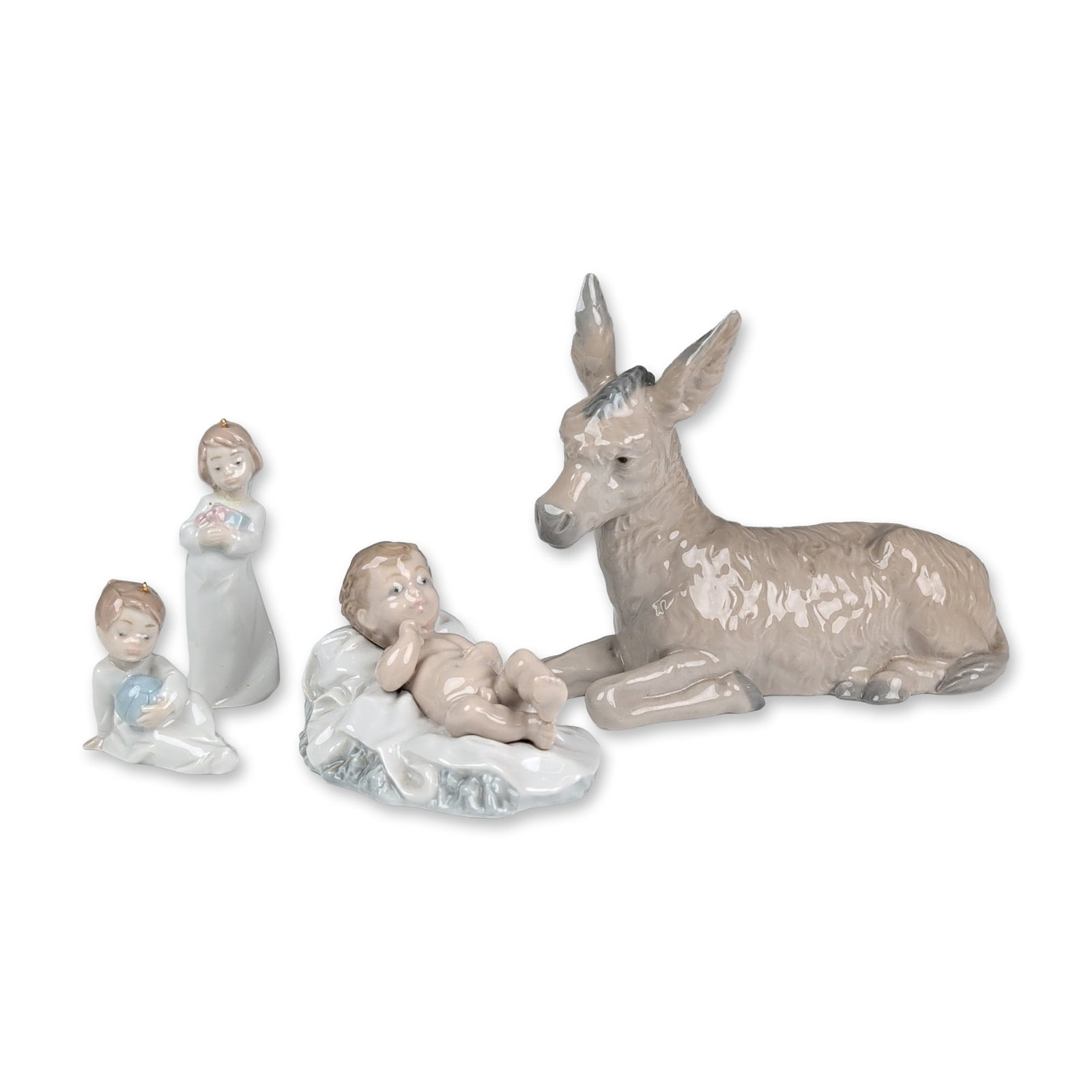 4pc Lladro and Nao Porcelain Figurines and Ornaments: Lladro and Nao. Group of four glazed porcelain figurines including a reclining nativity donkey, Baby Jesus in a manger, ornament of standing child in prayer, and a seated child holding a blue sphere o