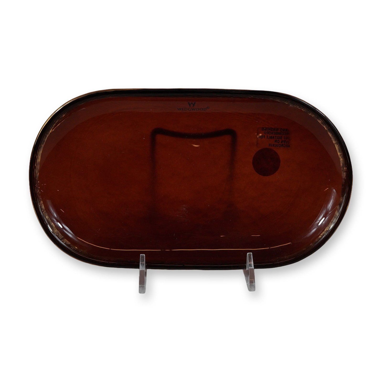 Wedgwood Topaz Amber Glass Jewelry Tray: A Wedgwood oval jewelry or vanity tray crafted from translucent glass in a deep amber-red hue. This piece features a wide, slightly upturned rim decorated with a textured pattern of fine concentric li