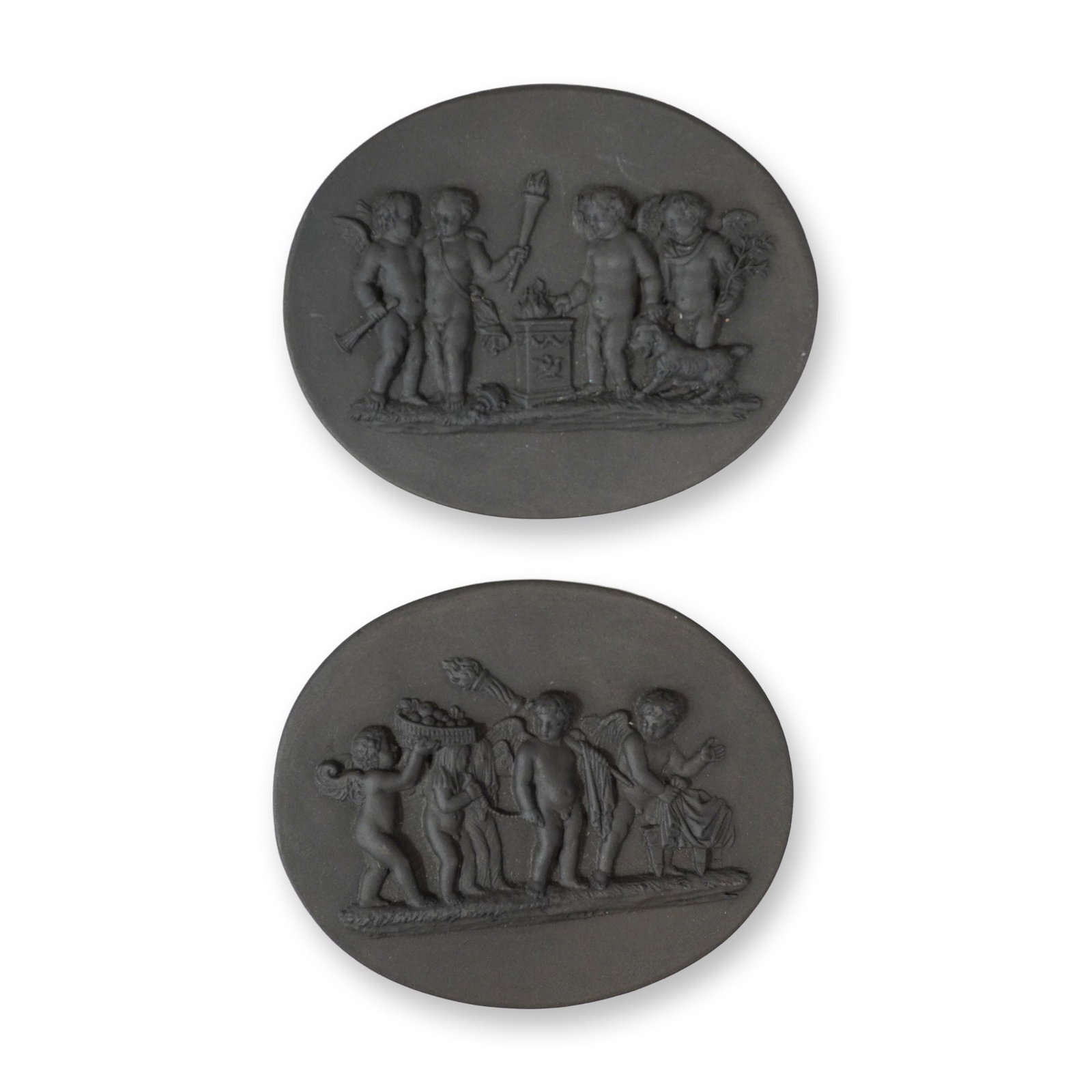 2pc Gordon Elliott Black Basalt Oval Plaques: Oval bas-relief plaques executed in black basalt stoneware by studio potter Gordon Elliott. The plaques feature neoclassical scenes involving groups of cherubs or putti. The first plaque depicts the S