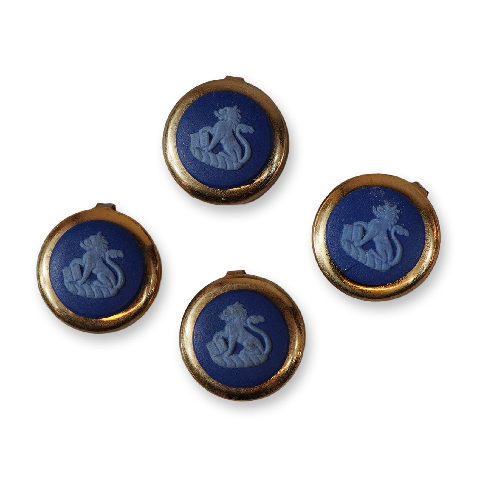 A Set of Four Wedgwood Gold-Toned Jasperware Button Covers: This set of four Wedgwood button covers features circular jasperware ceramic inserts in matte dark blue. Each insert is decorated with a light blue bas-relief motif of a lion rampant holding an open b