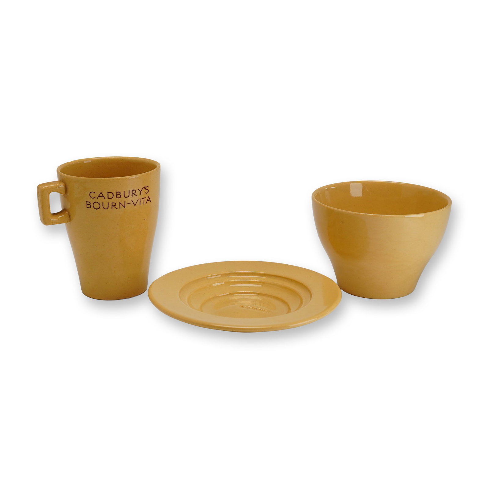 3pc Wedgwood Cup and Saucer Set for Cadbury Bourn-vita: This three-piece glazed earthenware promotional set was produced by Wedgwood for Cadbury's Bourn-vita following the malted chocolate drink's 1932 launch. Featuring a uniform mustard yellow glaze and A