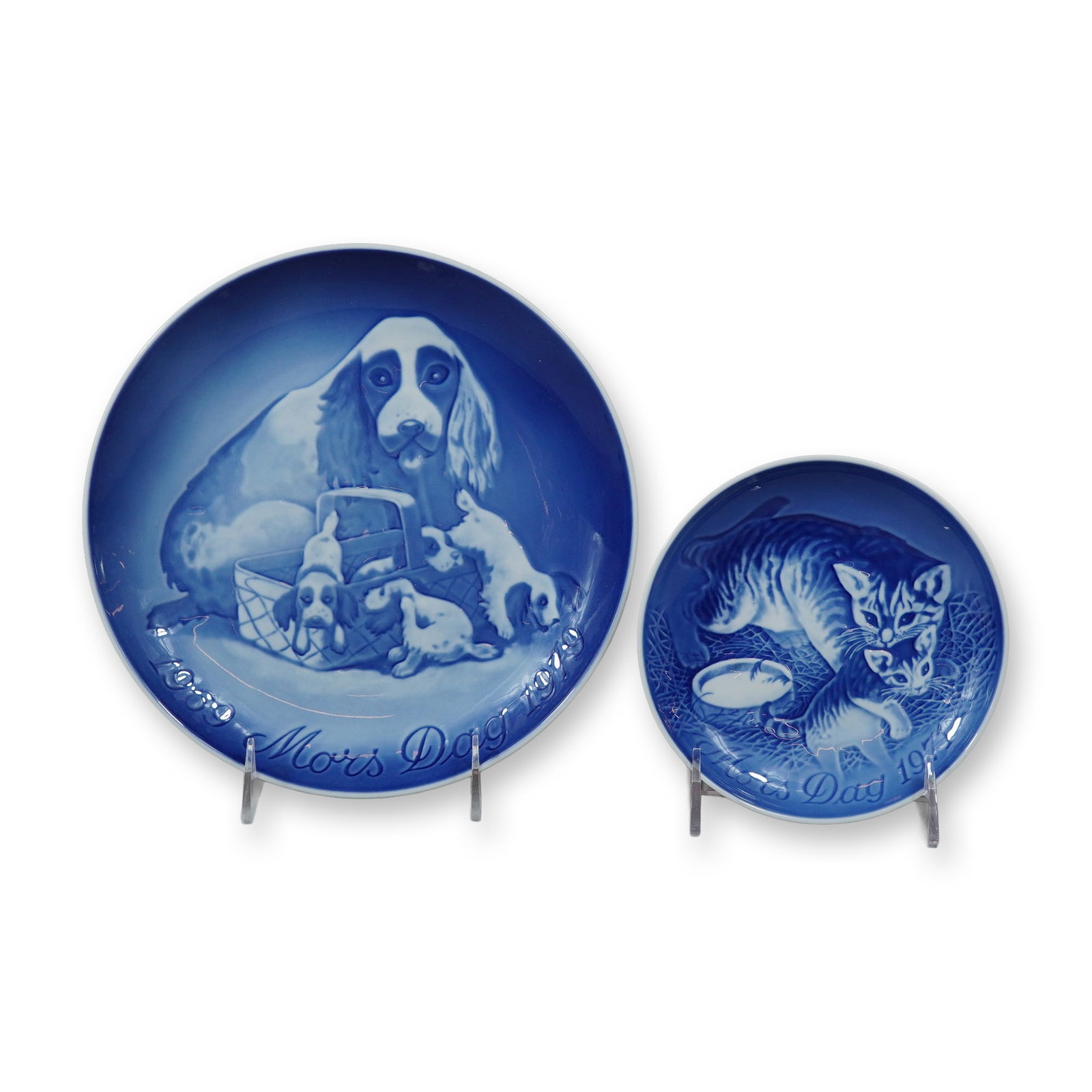 2pc Bing and Grondahl Copenhagen Porcelain Mothers Day Plates: This lot features a 1971 Mother's Day kitten bread plate and a 1979 Mother's Day spaniel dinner plate manufactured by Bing and Grondahl of Copenhagen, Denmark. Both plates are decorated in the company