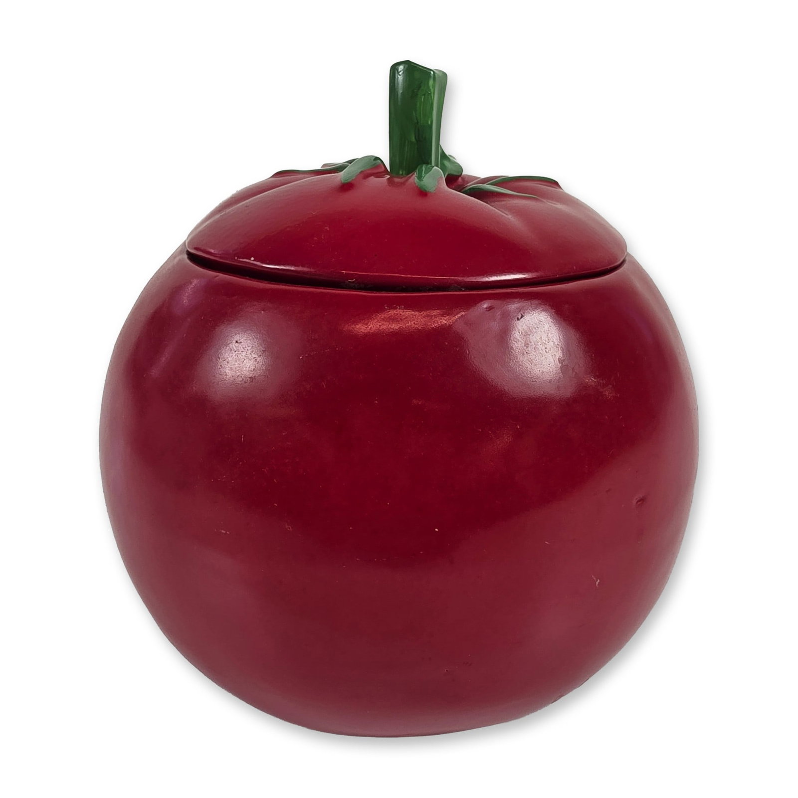 McCoy Pottery Red Ceramic Tomato Cookie Jar: Vintage McCoy Pottery tomato-form cookie jar in red glazed earthenware. The piece is realistically modeled as a ripe tomato with a high-gloss glaze. The conforming lid is finished with a green glaze