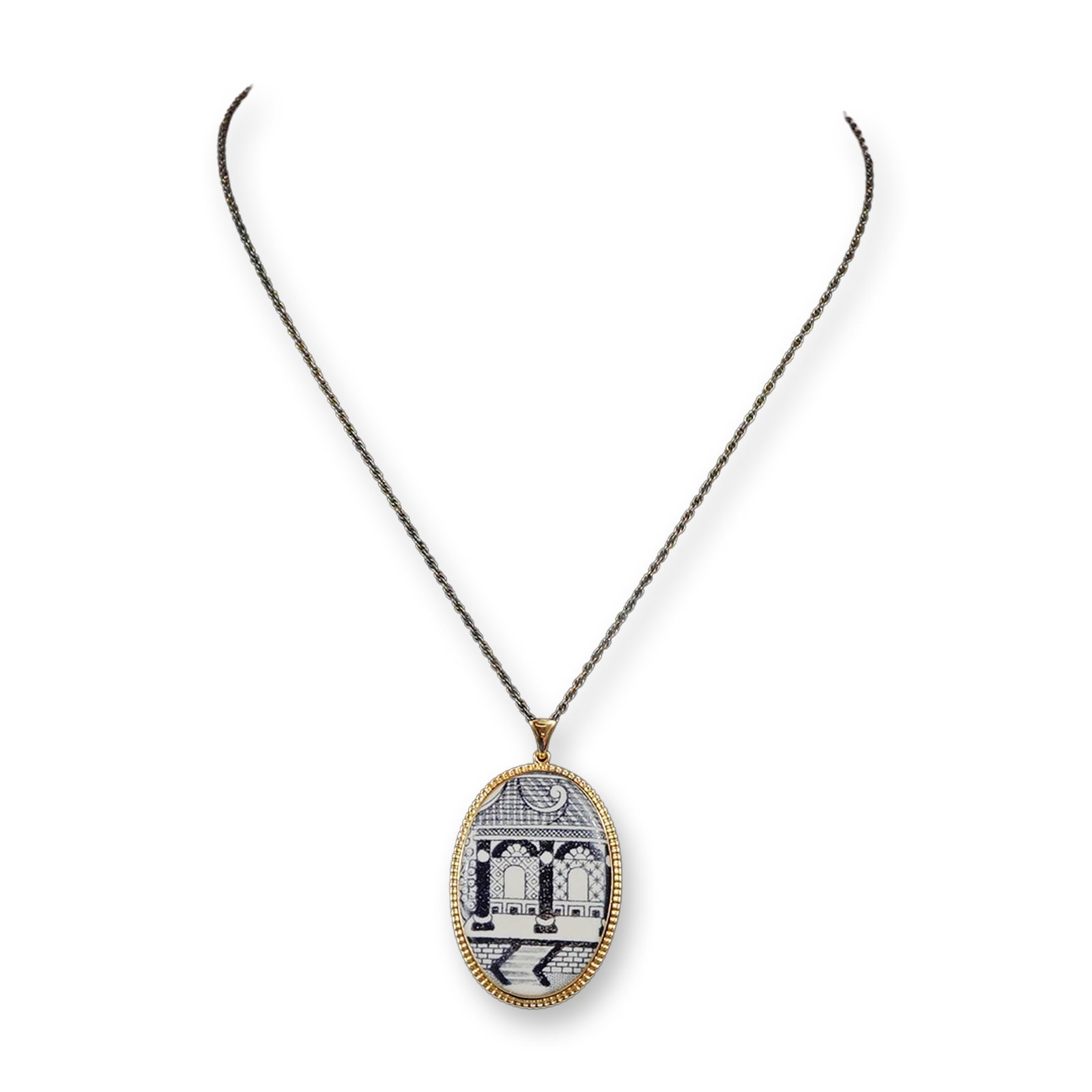 Gold Plated Wedgwood Porcelain Pendant Necklace: This vintage pendant necklace features an oval porcelain insert manufactured by Wedgwood in England. The porcelain is decorated with a blue transfer-printed architectural scene depicting classical