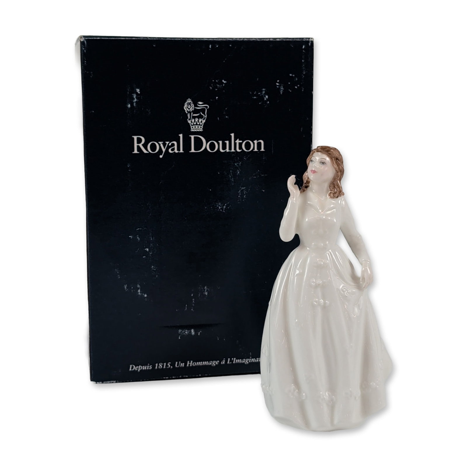Royal Doulton Joy HN 3875 Porcelain Figurine: Royal Doulton. Figurine in glazed bone china titled Joy, model number HN 3875. The figure depicts a young woman in a white gown with embossed floral relief and brown hair. Modelled by artist Nada M. P