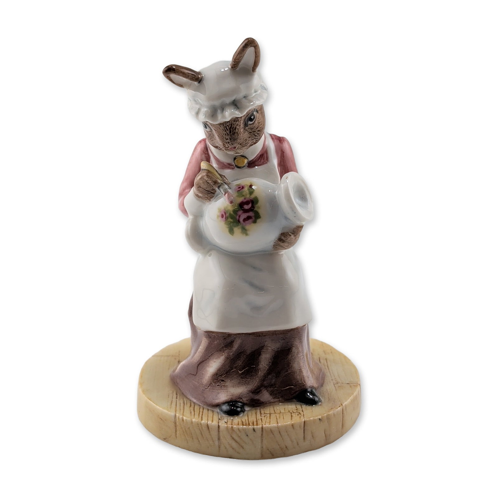 Royal Doulton LE Bunnykins Figurine, Paintress DB465: Royal Doulton. Paintress Bunnykins DB465 porcelain figurine modeled by Shane Ridge. The rabbit character is seated on a stool wearing a pink bodice and white apron, holding a vase hand-painting a flor