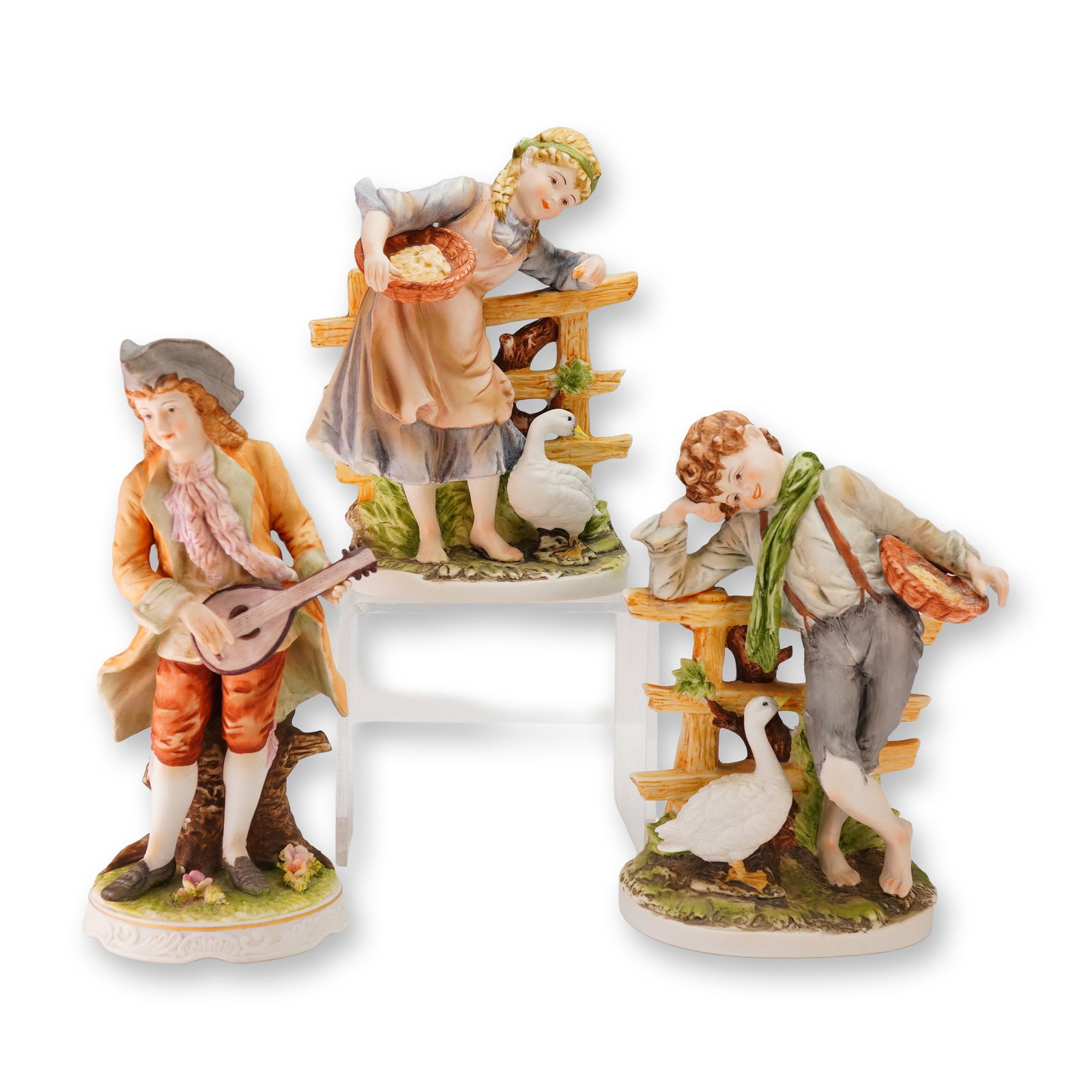 A Group of Three Polychrome Porcelain Figurines: A group of three polychrome hand-painted porcelain figurines, executed in a Rococo-revival style. The group includes a pair of figures attributed to Lefton, depicting a young woman and a young boy, ea