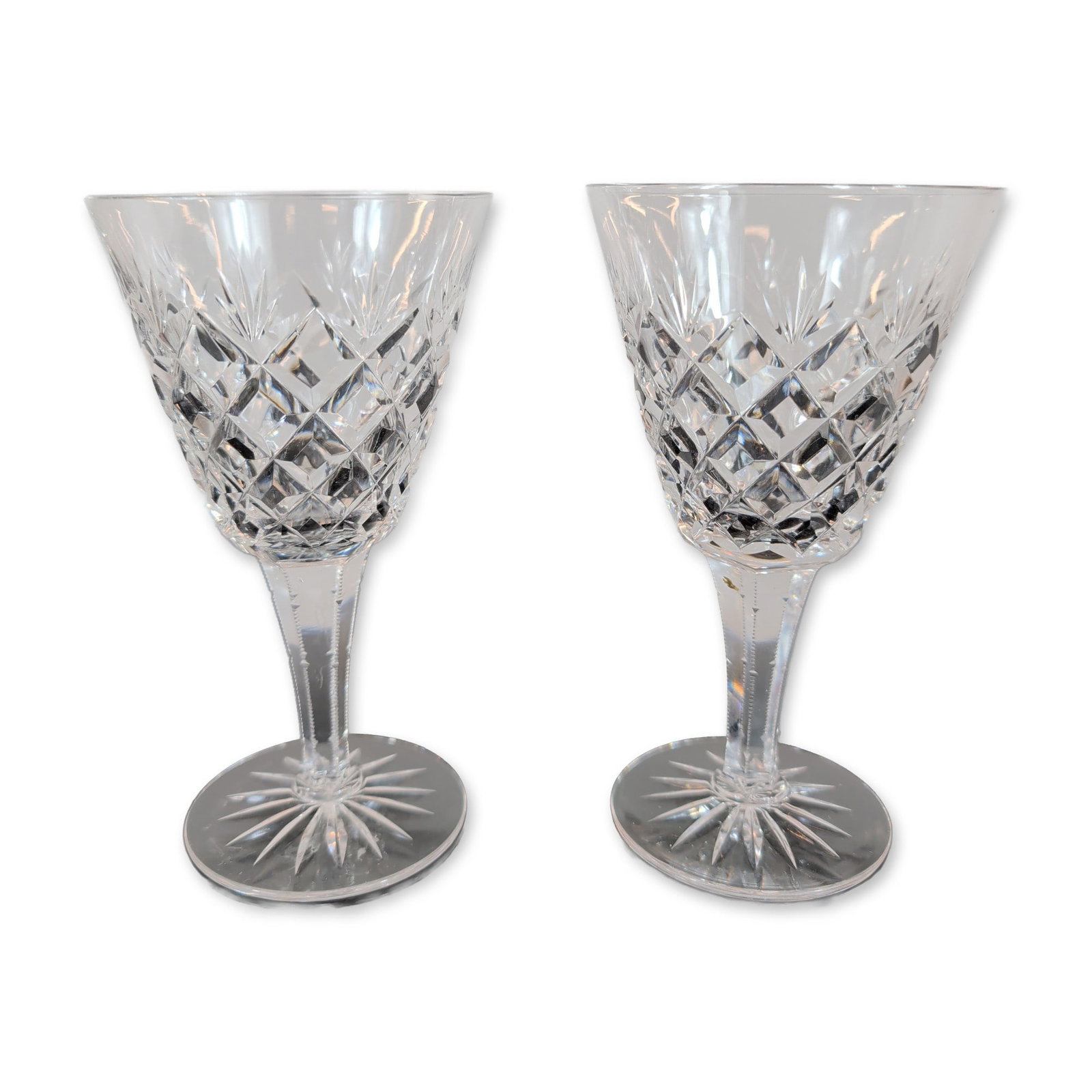 Pair of Crystal Wine Glasses: Pair of wine glasses, crafted in lead crystal. The bowls feature a lower band of deep-cut diamond patterns surmounted by vertical wedge cuts. The six-sided faceted stems lead to circular feet
