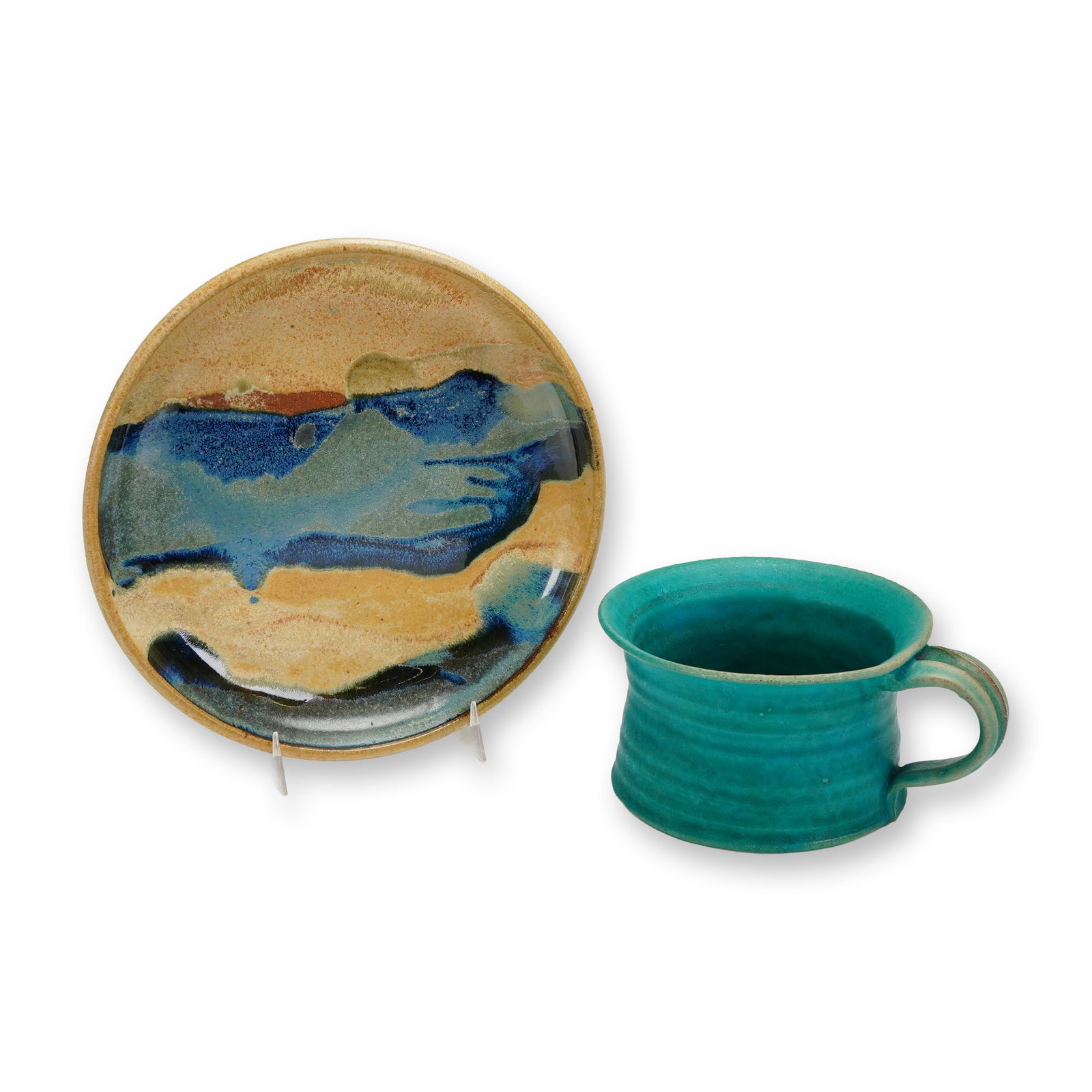 2pc Contemporary Studio Pottery Stoneware Cup and Plate: The plate is executed in glazed stoneware and features a glossy abstract glaze design combining mottled tan and ochre fields with dramatic flowing streaks of deep cobalt blue, turquoise, and black.