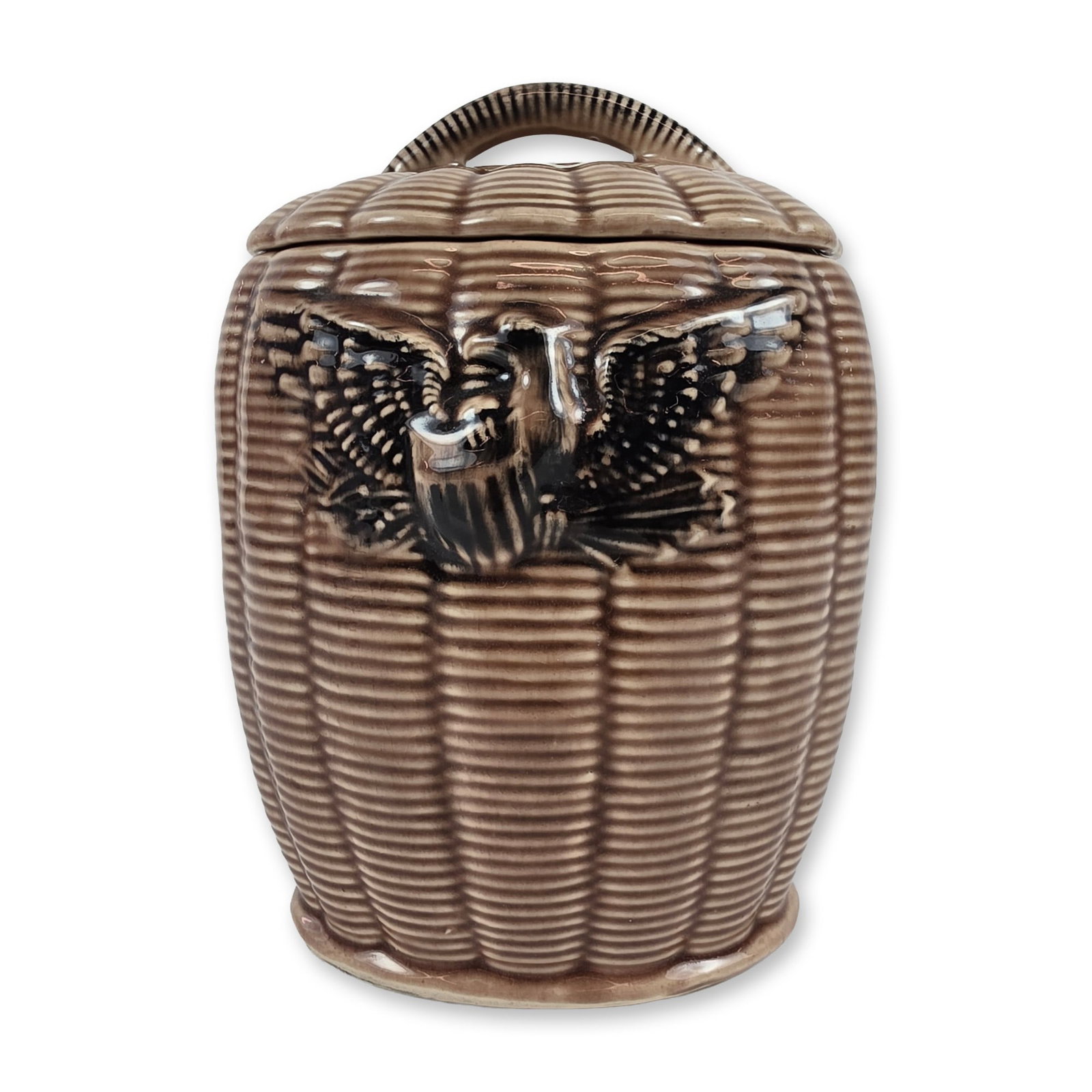 McCoy Ceramic American Eagle Cookie Jar: Lidded ceramic cookie jar featuring a cylindrical body with an all-over molded basketweave texture. The front is decorated with a relief-molded Federal-style American eagle with outspread wings clutch