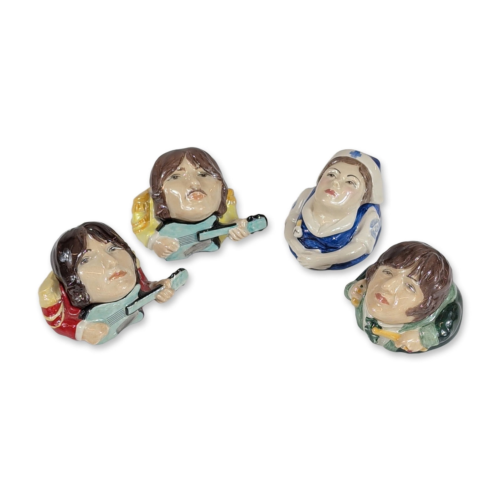 Group of Four Kevin Francis Face Pots: Kevin Francis, England. Group of four ceramic face pots in polychrome glaze. Included are two George Harrison figures in red and yellow jackets holding guitars, one Ringo Starr figure in a green jacke