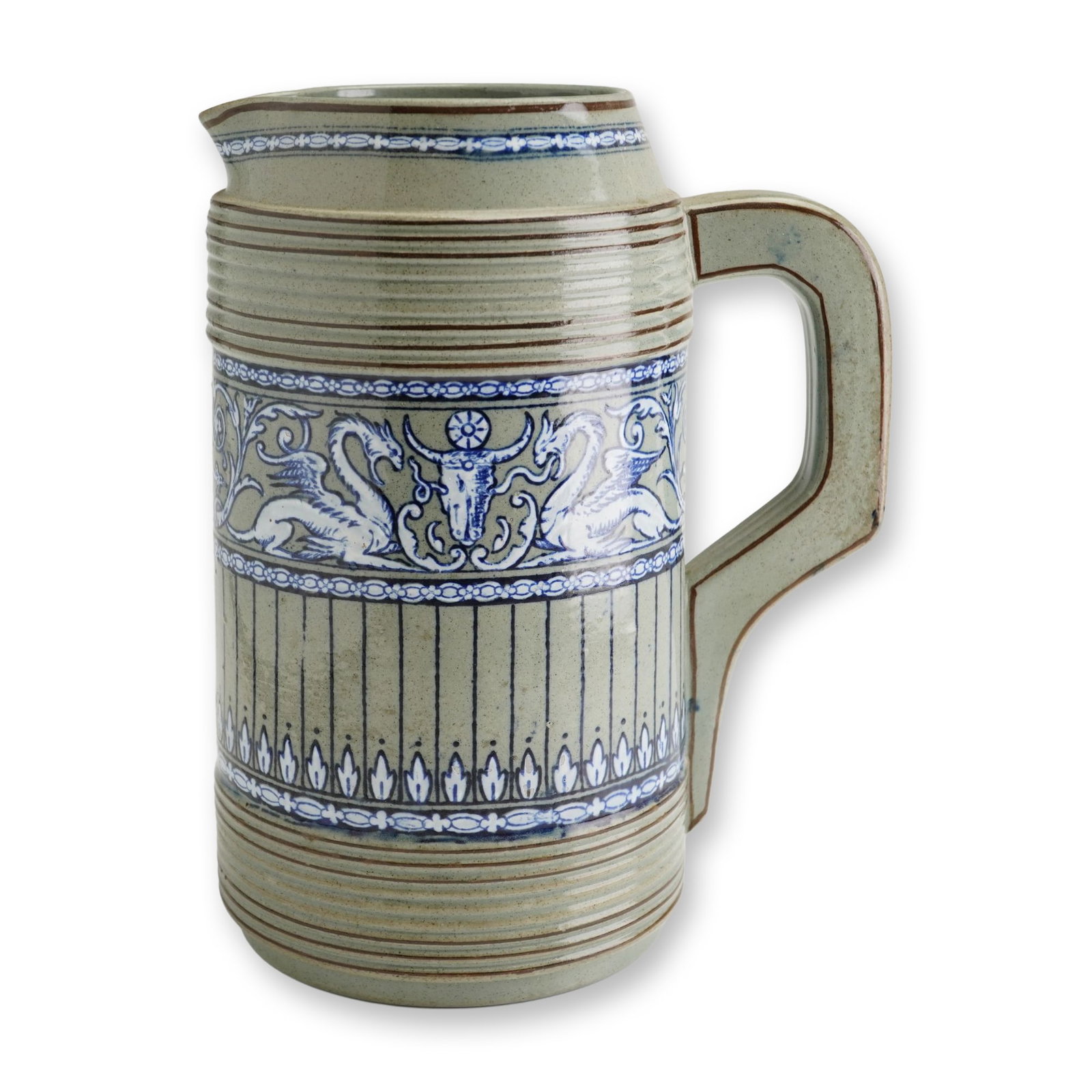 Wedgwood Salt-Glazed Reeded Pitcher with Winged Dragons and Bucranium: This salt-glazed stoneware pitcher is a product of Wedgwood, executed in the German Westerwald revival style. The tall, cylindrical body features horizontal reeded bands throughout, highlighted by cob