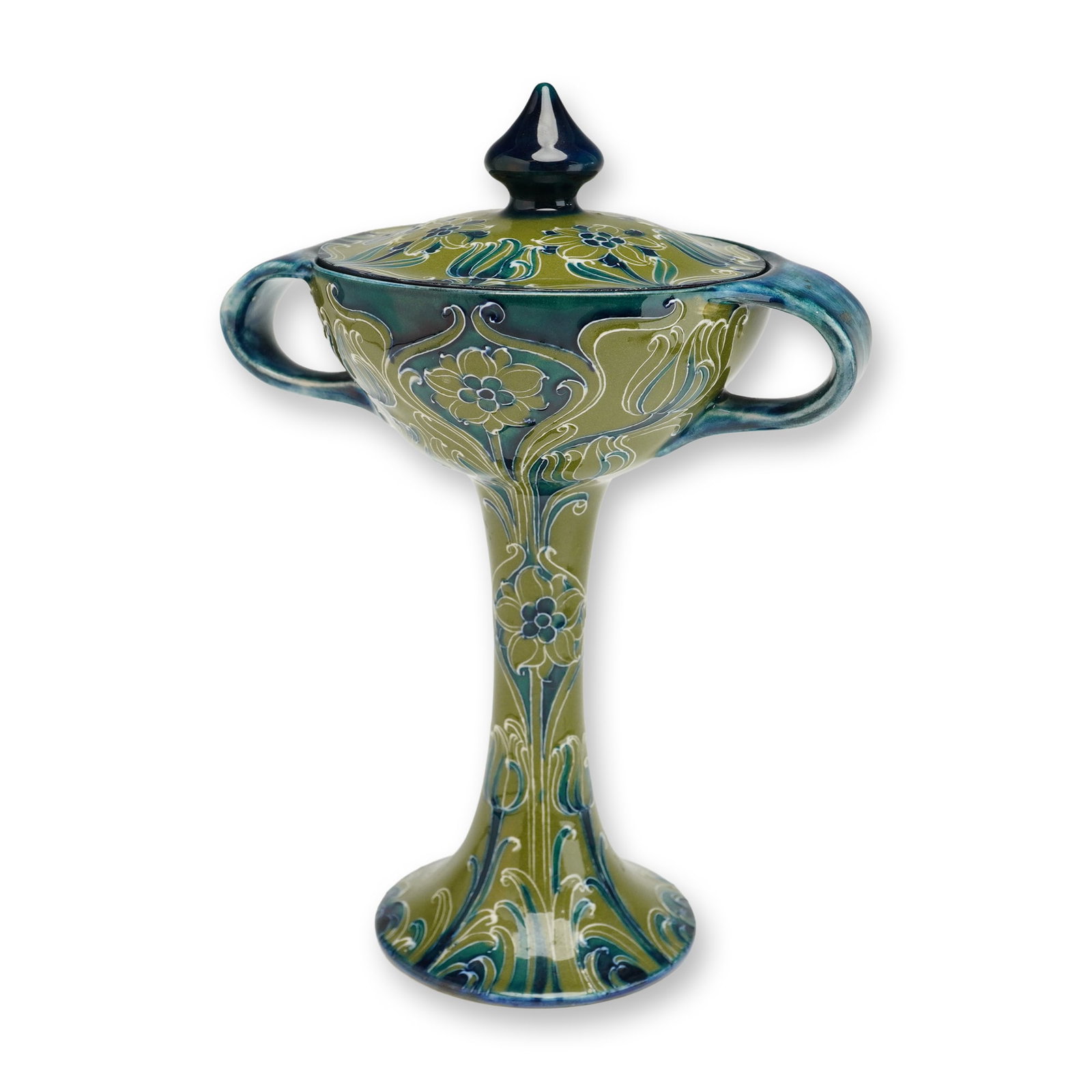 James Macintyre by William Moorcroft Florian Ware Lidded Bonbonniere: This vessel features a slender stem rising from a widely flaring circular foot, with two prominent stylized handles framing a broad rim. The body and lid are finished in a green and blue ground, adorn