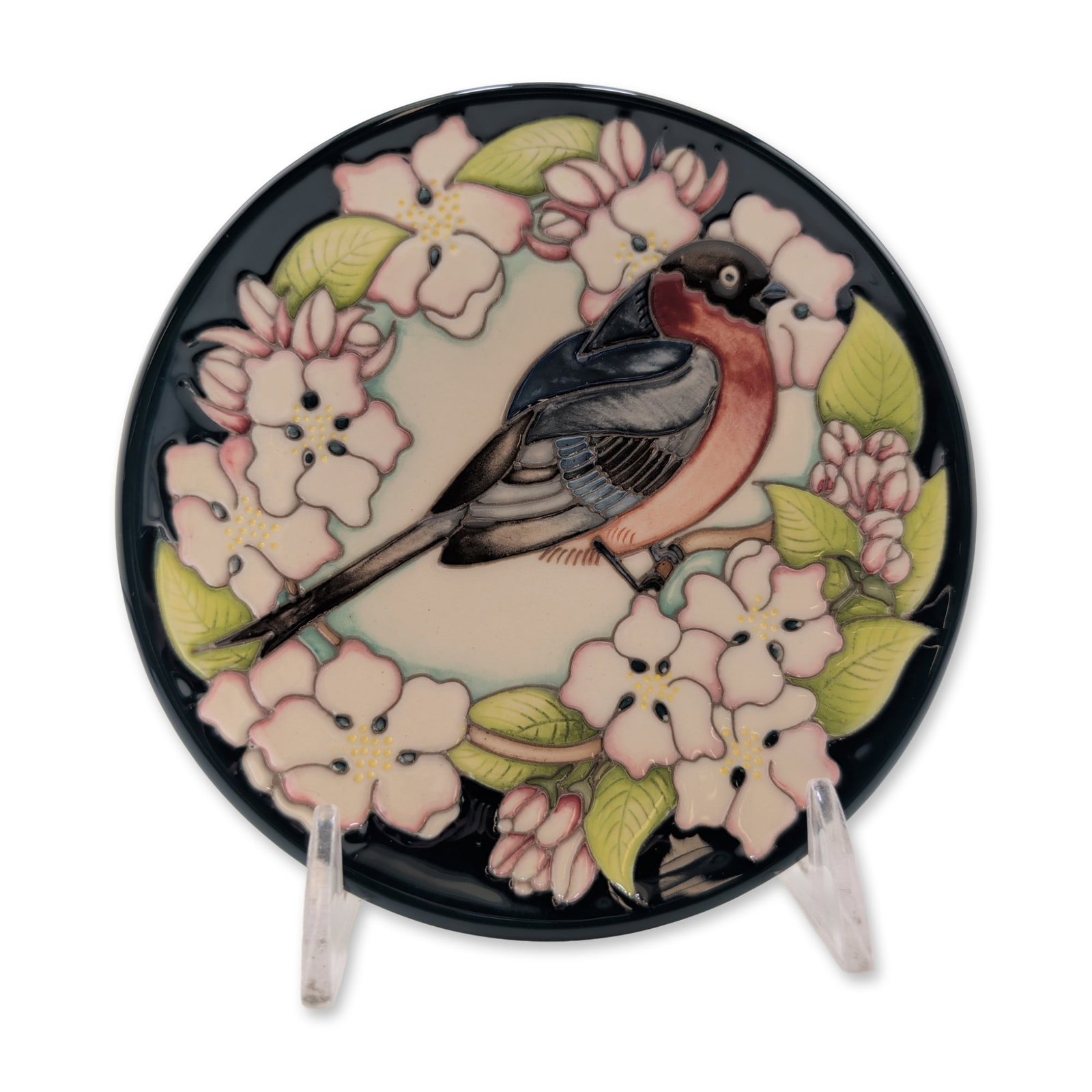 Moorcroft Pottery Trial Bullfinch and Floral Motif Plate: Circular decorative trial plate in tube-lined earthenware, featuring a bullfinch bird perched amidst pink apple blossoms and green leaves. The design transitions from a cream-toned center to a deep na