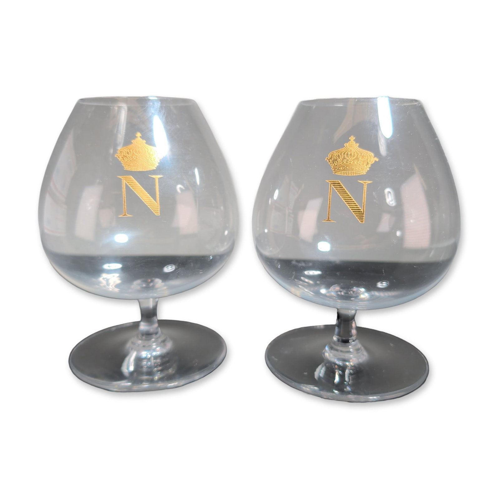 2pc Baccarat France Crystal Napoleon Brandy Snifters: Baccarat, France, pair of brandy snifters in clear crystal, featuring gilded Napoleonic N ciphers surmounted by imperial crowns. Each snifter comprises a wide-bodied balloon bowl on a short stem and c