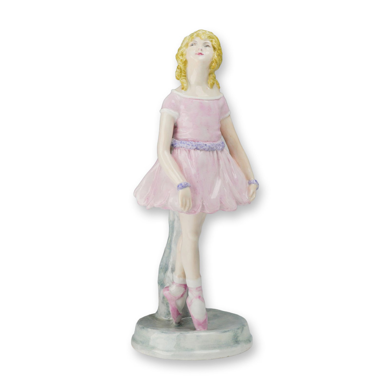 Wedgwood Bone China Figurine of a Ballerina by Kathleen Goodwin: This hand-painted bone china figurine depicts a young ballerina, modeled by artist Kathleen Goodwin for Wedgwood. The standing figure is shown in a graceful pose, looking upward and to her right. She 