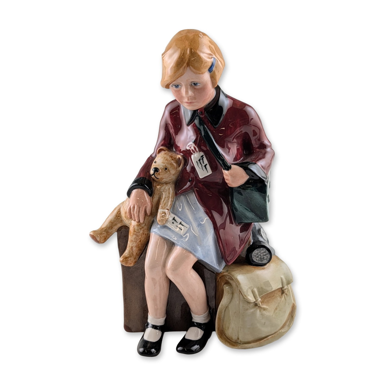 Royal Doulton "The Girl Evacuee" Porcelain Figurine: Royal Doulton, circa 1988. Porcelain figurine titled "The Girl Evacuee" HN 3203, modeled by Adrian Hughes for the "Children of the Blitz" series. Hand-painted bone china figure depicting a young girl 