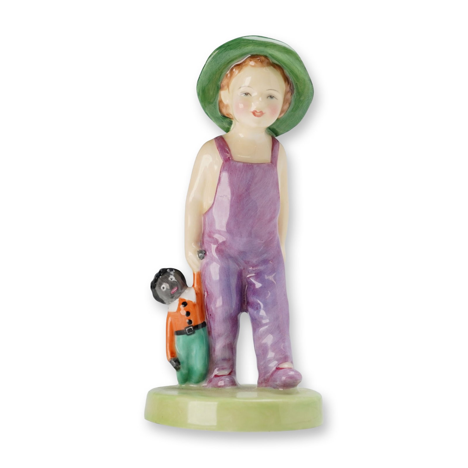 Royal Doulton Colorway Bone China Figurine, Gollywog HN2040: Designed by Leslie Harradine. The figure depicts a child wearing purple overalls and a green wide-brimmed hat, holding a traditional rag doll in the right hand. The base features the Royal Doulton bac
