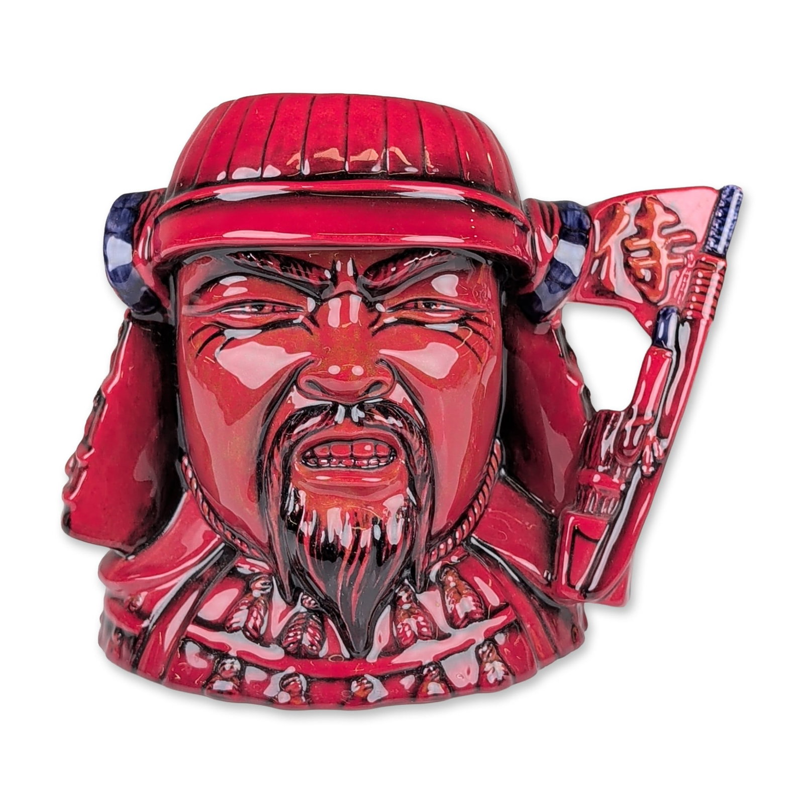 Royal Doulton Flambe Prototype Large Character Jug, Samurai: Featuring a Japanese Samurai figural jug finished in a red flambe glaze. The figure is depicted with a fierce facial expression, pointed beard, and mustache, wearing a traditional kabuto helmet with h